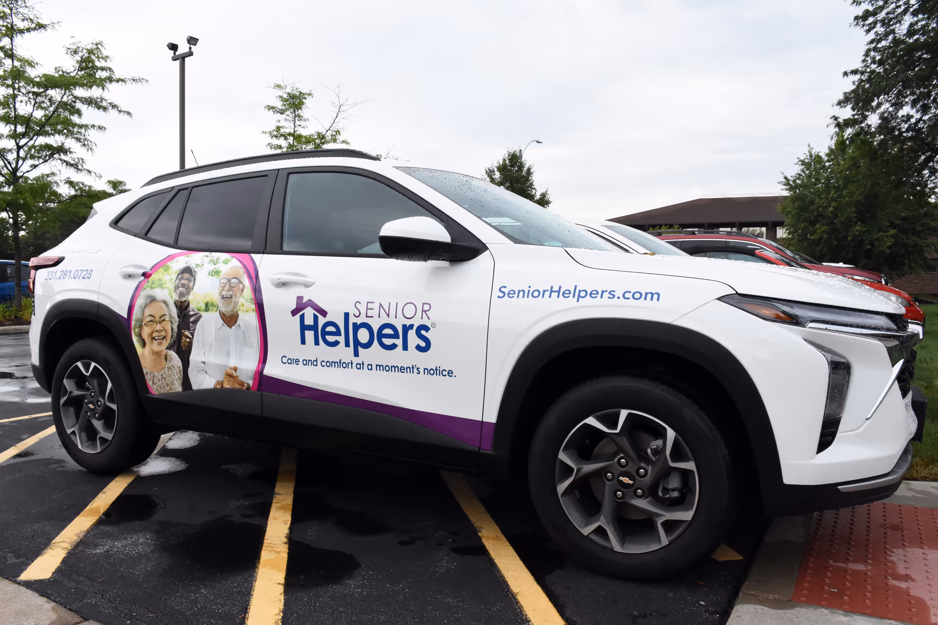 White SUV wrapped with Senior Helpers branding parked in a wet parking lot.