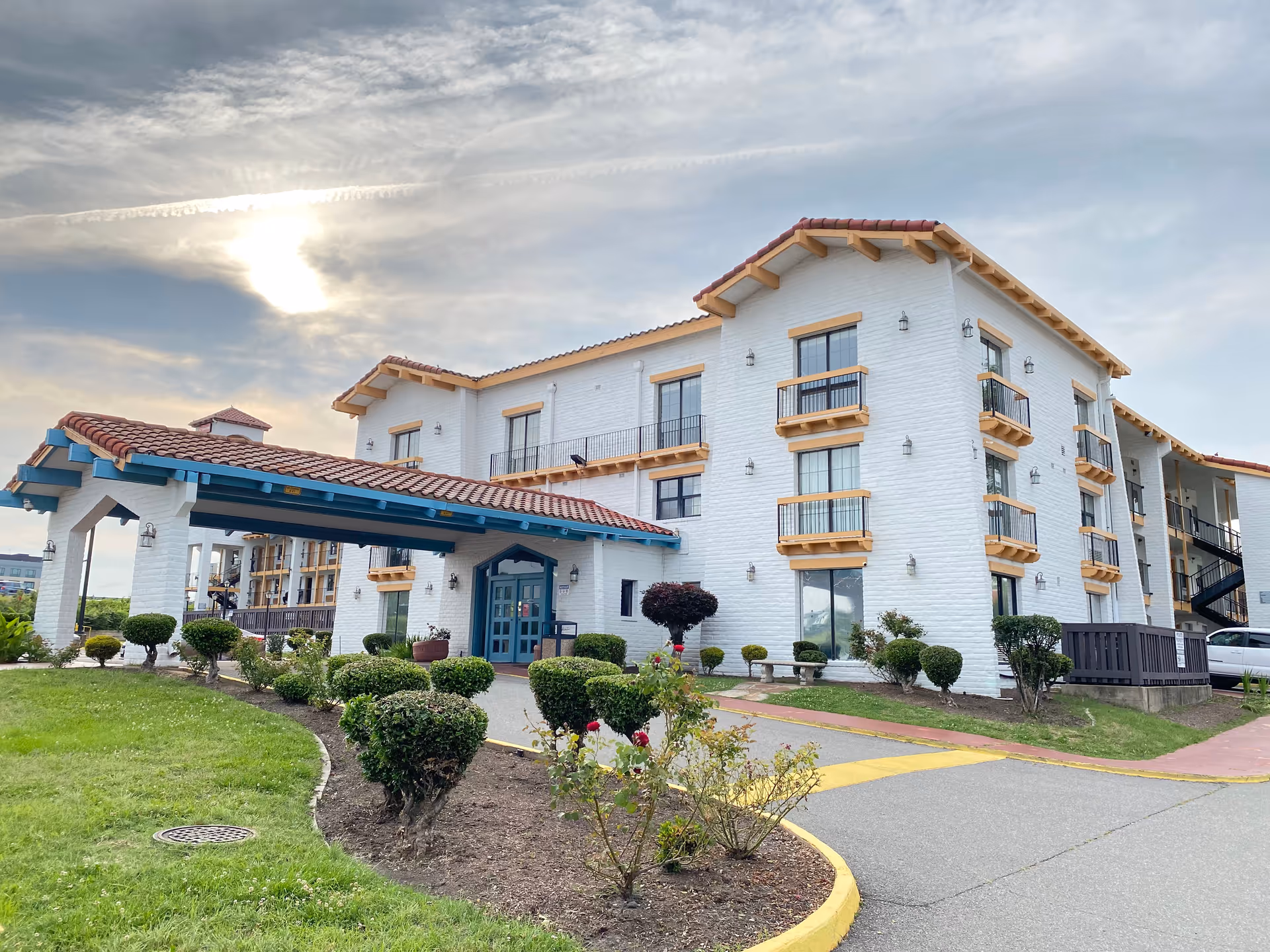 White multi-story senior living building with a blue entrance canopy and landscaped grounds.