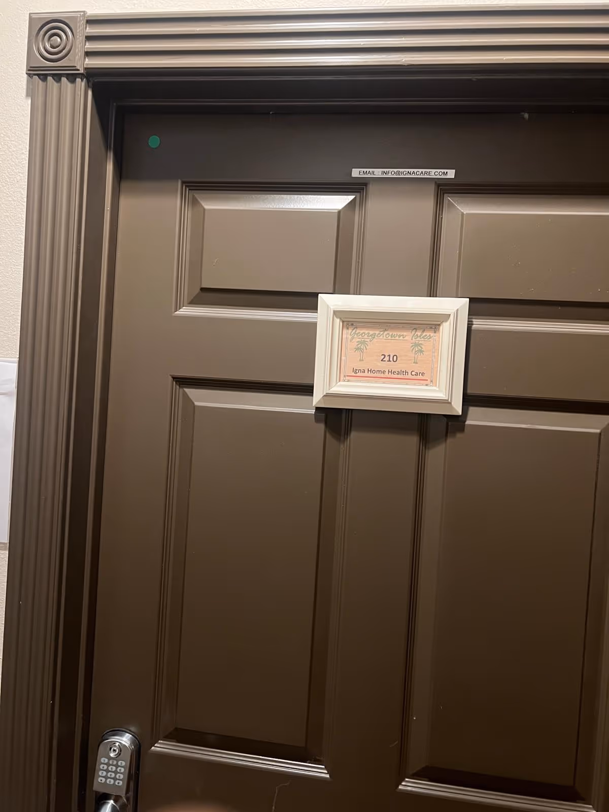 Brown interior door in hallway with sign plaque and keypad lock