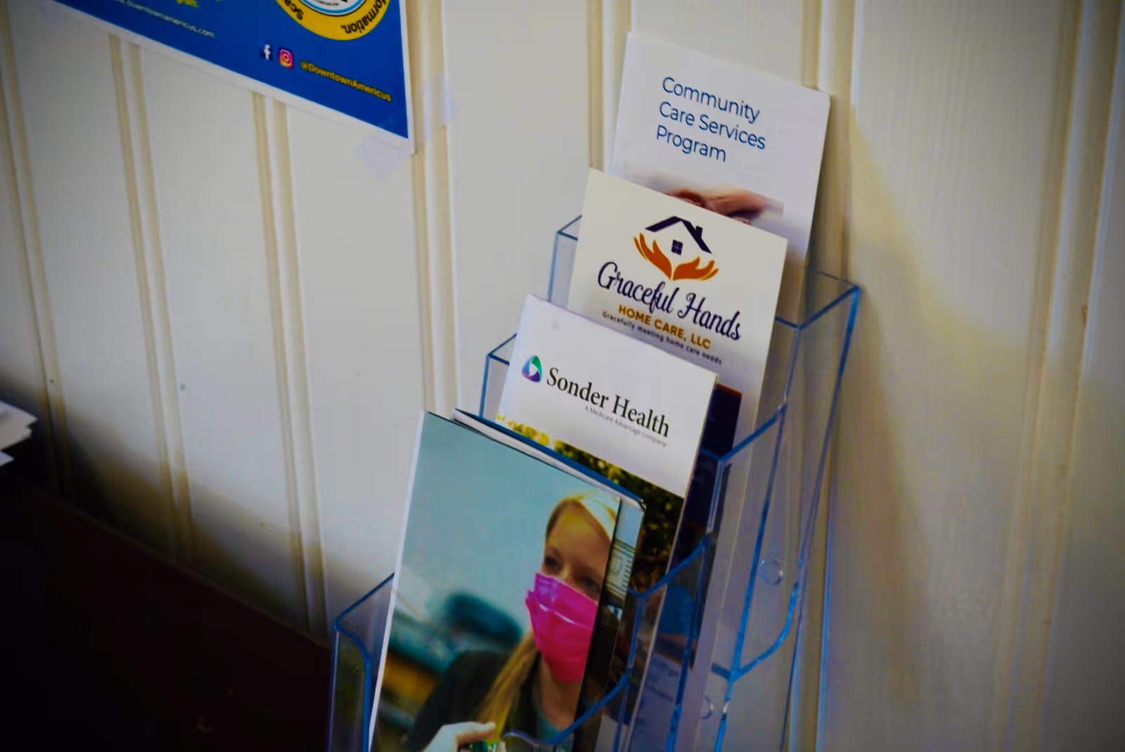 Brochure rack with Graceful Hands Home Care materials in an interior facility hallway.