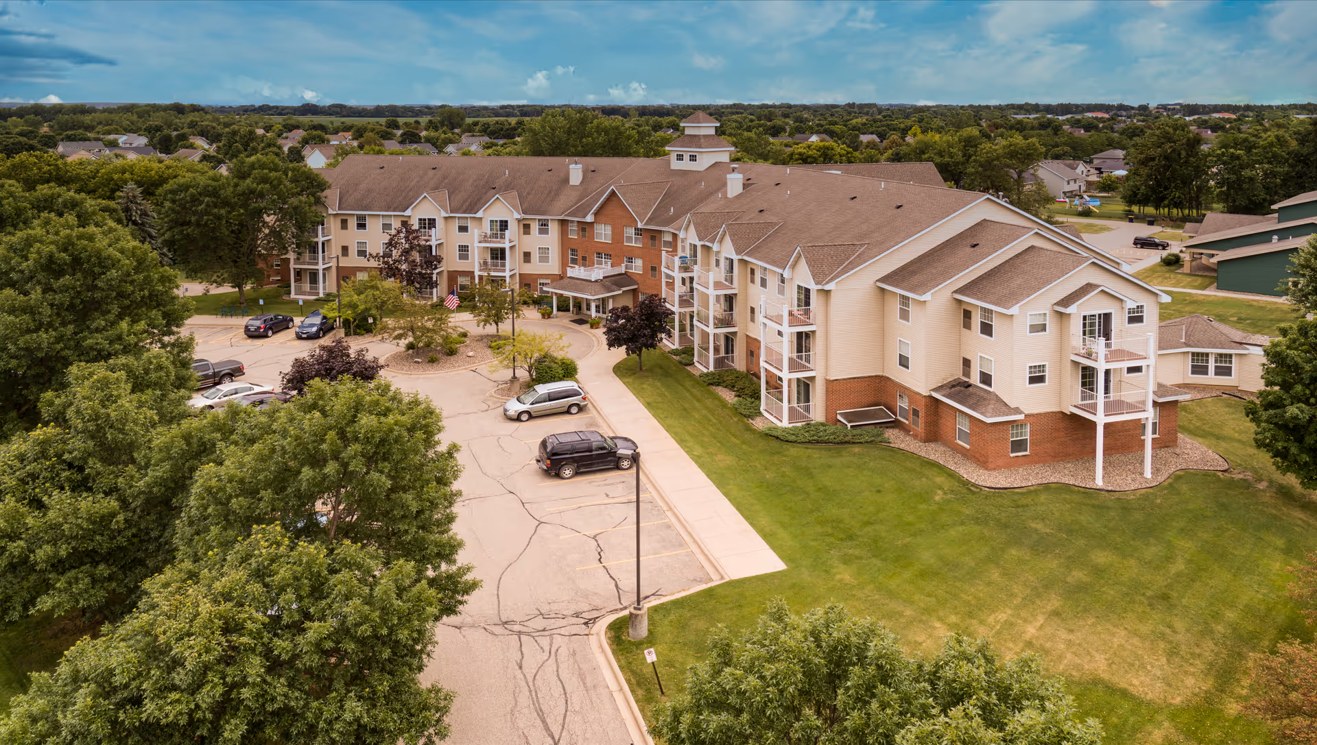 Aerial view of a Trinity Care Center senior living building with parking lot and green lawn.