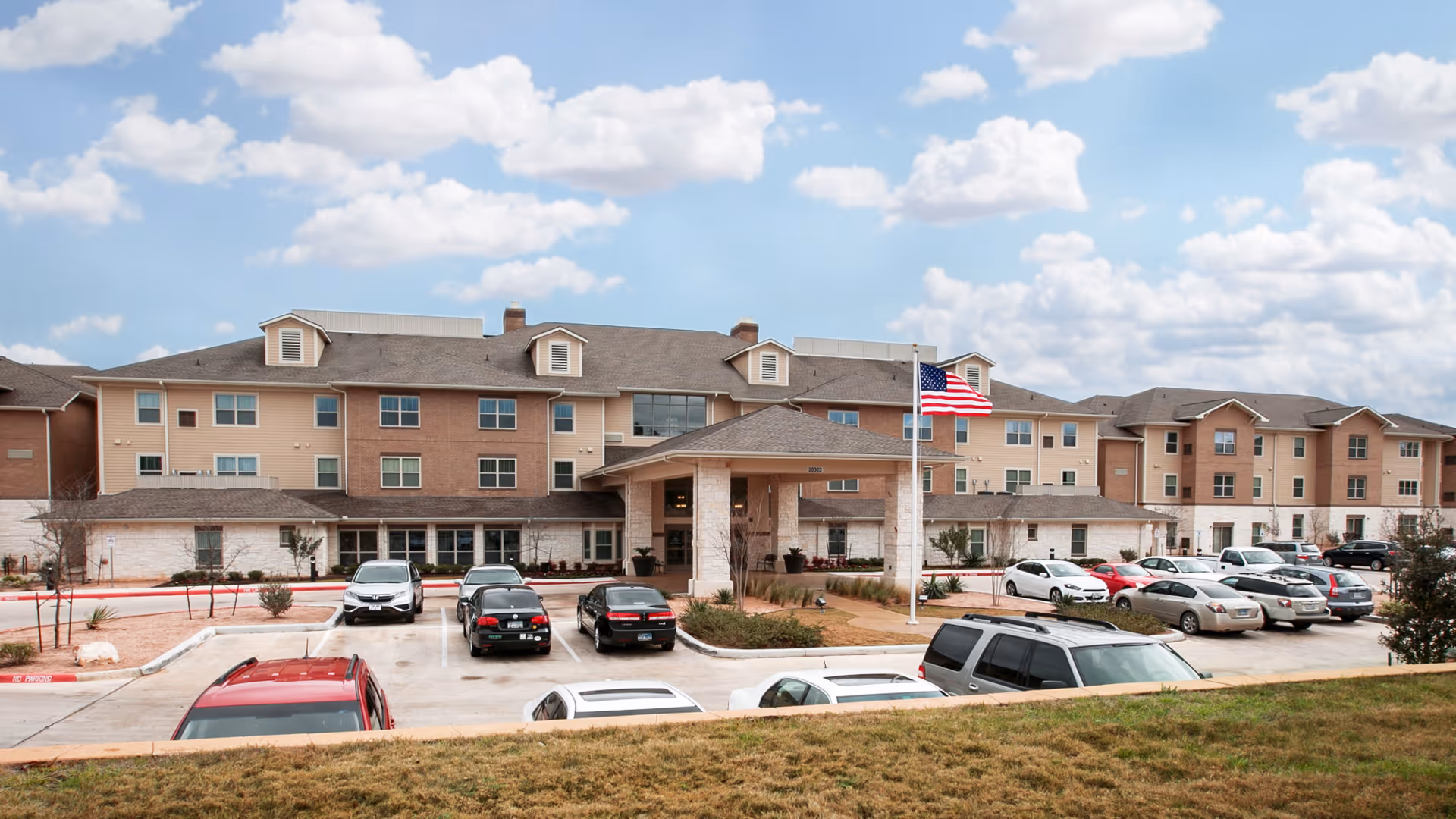 Exterior view of Emerald Oaks Retirement Resort with parked cars and entrance canopy.