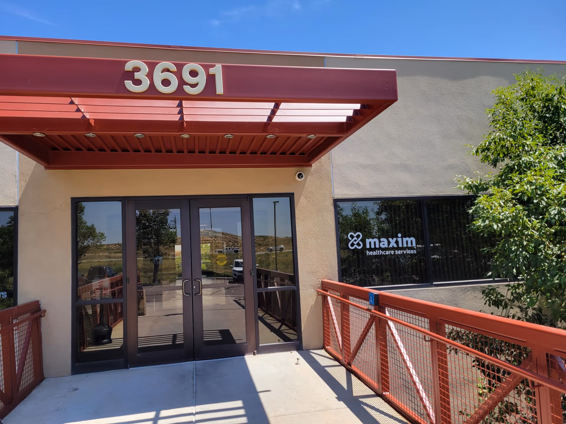 Entrance to Maxim Healthcare Pueblo Regional Office with glass doors and a red canopy.