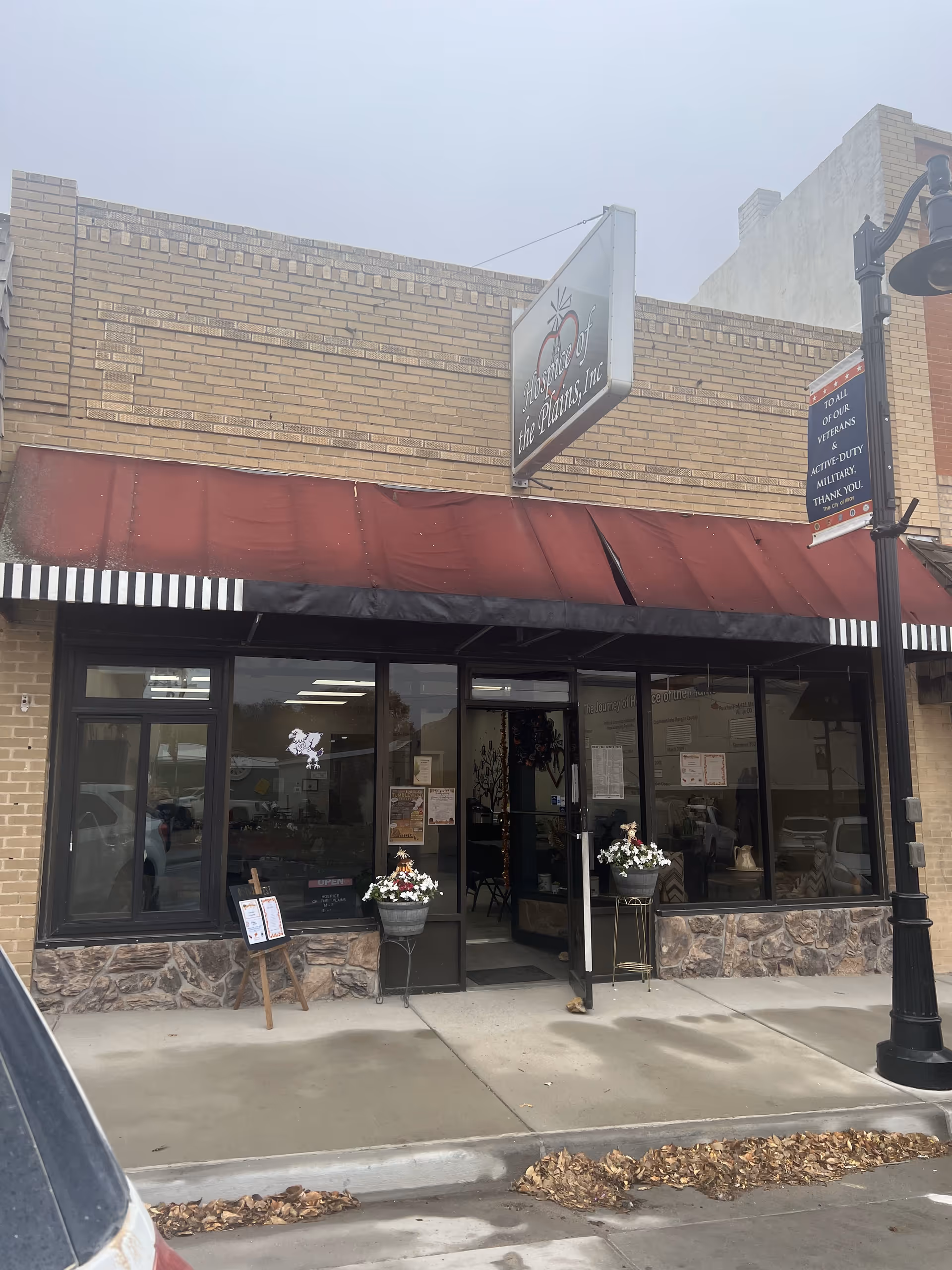Exterior view of Hospice of the Plains storefront with maroon awning and glass doors.