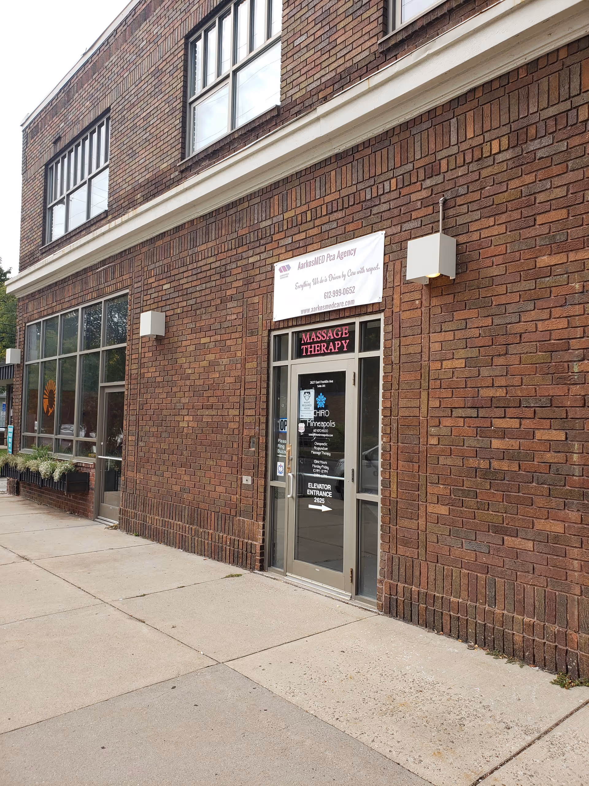 Brick building exterior with glass entrance and massage therapy sign.
