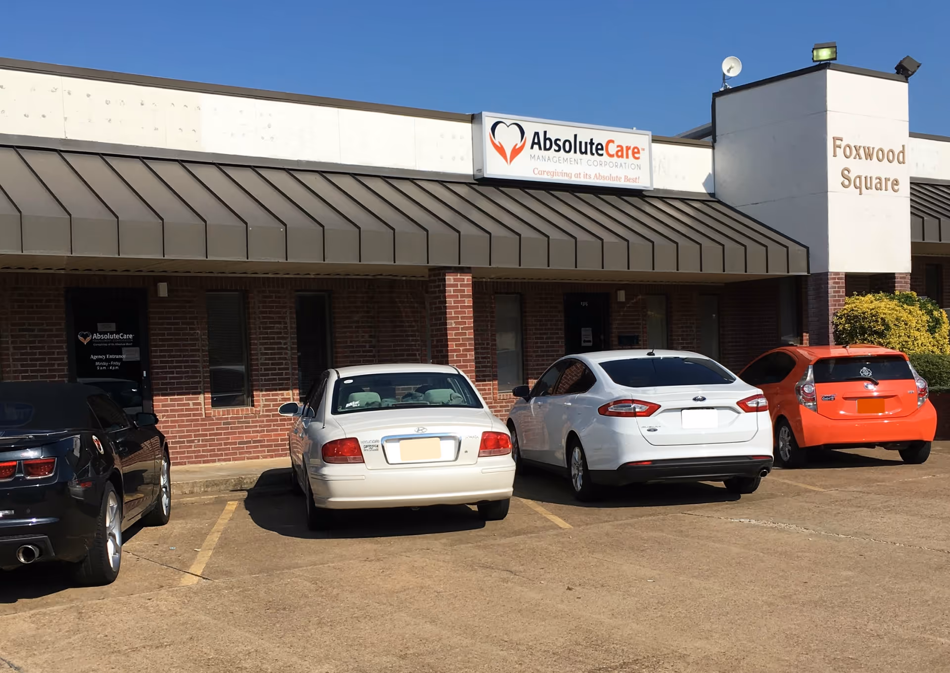 Exterior view of a storefront with AbsoluteCare sign and parked cars.
