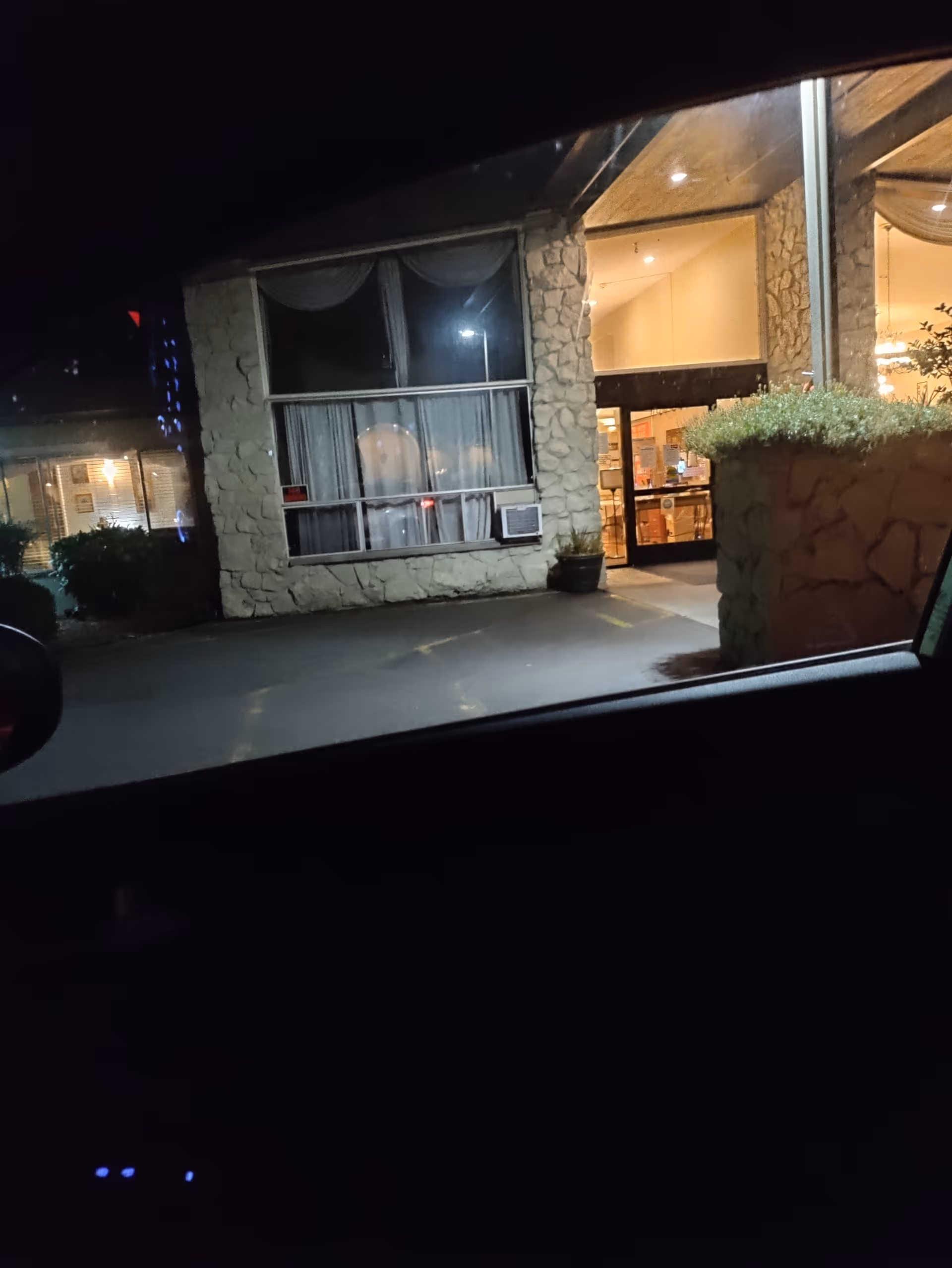 Night view of a retirement community entrance with glass doors and stone exterior.