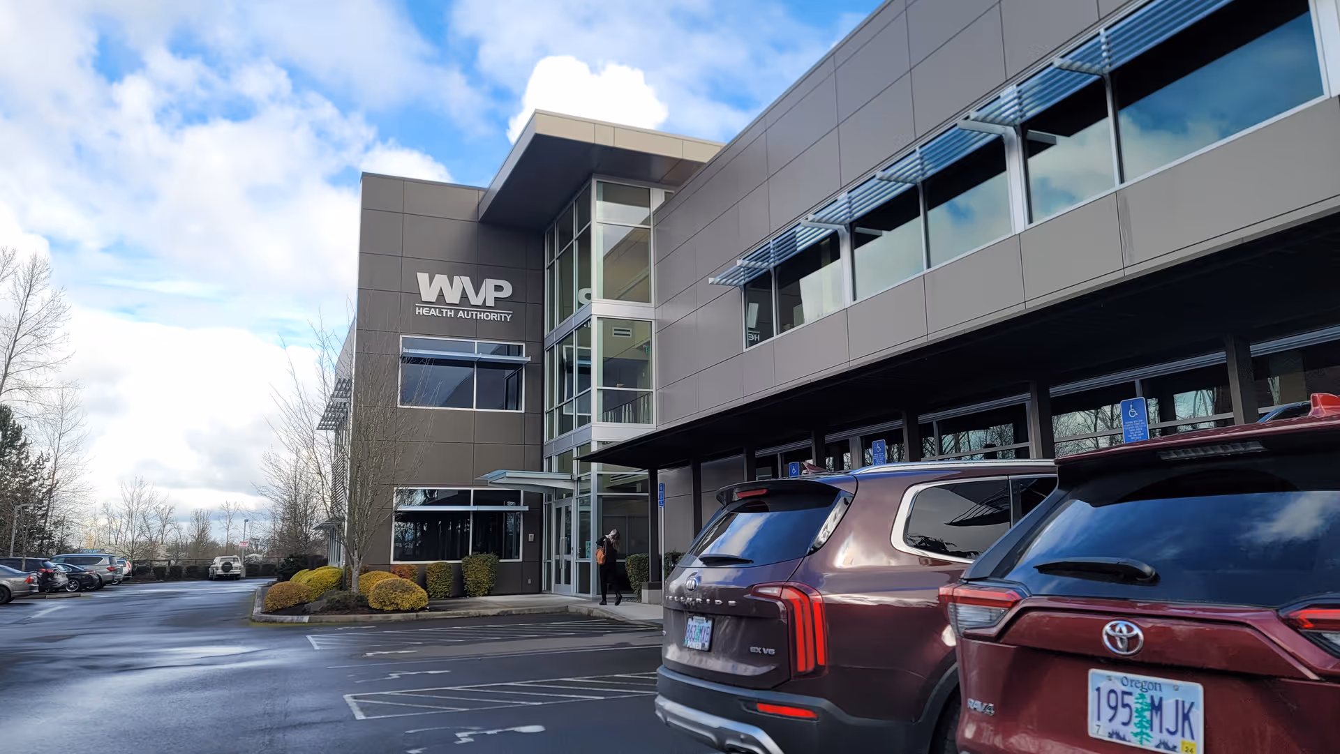 Modern WVP Health Authority building exterior with a parking lot and cars.