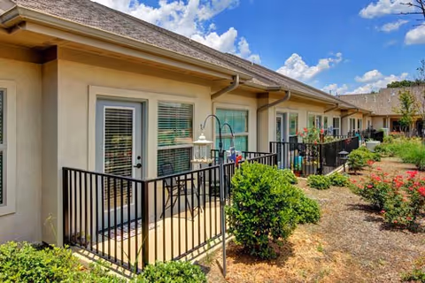 Exterior view of a senior living facility with patios, railings, and landscaping.