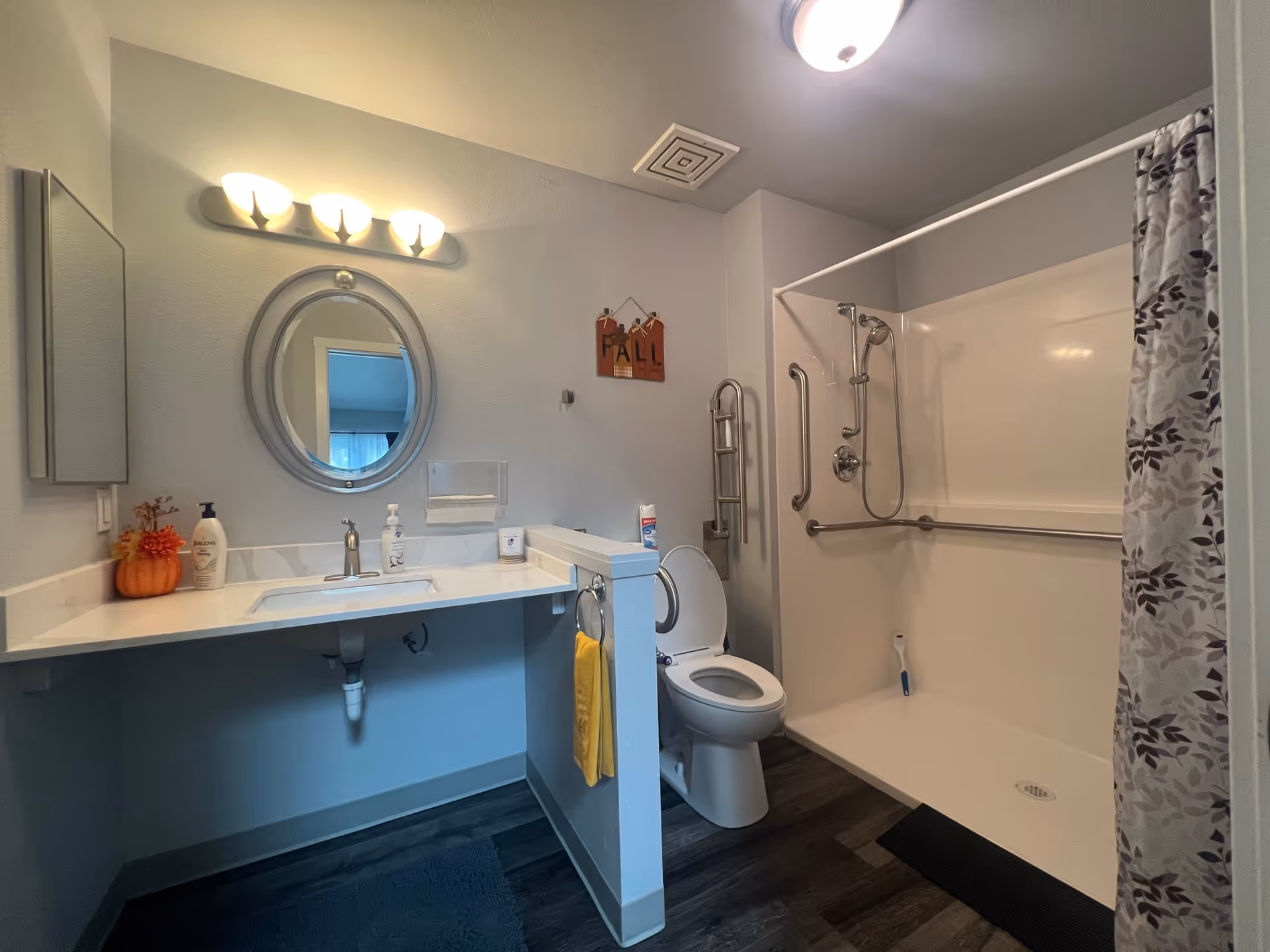 Senior living bathroom featuring sink, round mirror, toilet, and walk-in tub.