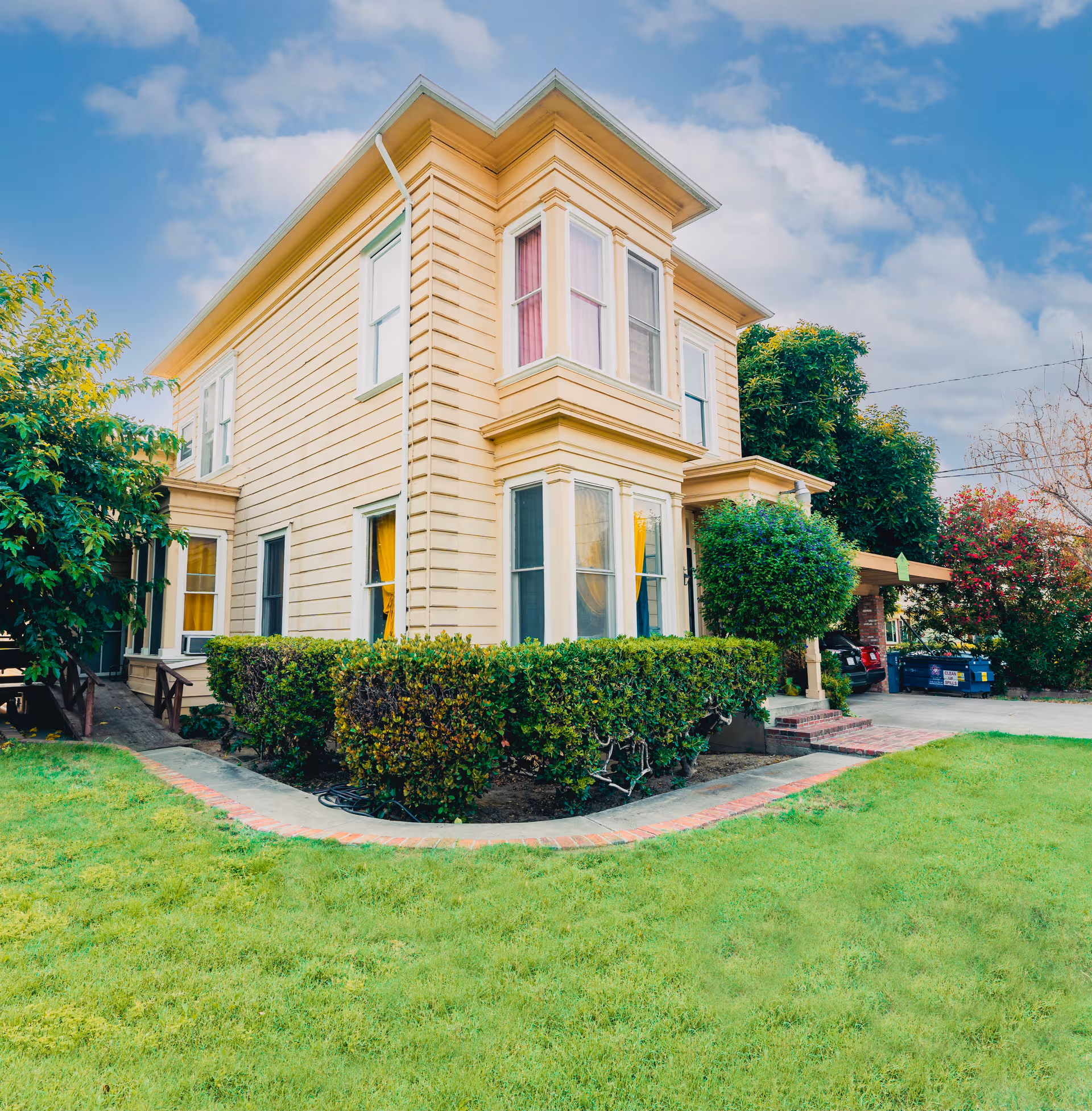Two-story beige Bonnevie Residence and Care exterior with manicured lawn and shrubs.