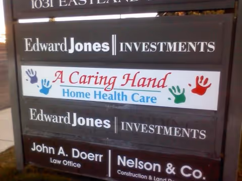 Outdoor building signboard showing Edward Jones Investments and A Caring Hand Home Health Care.