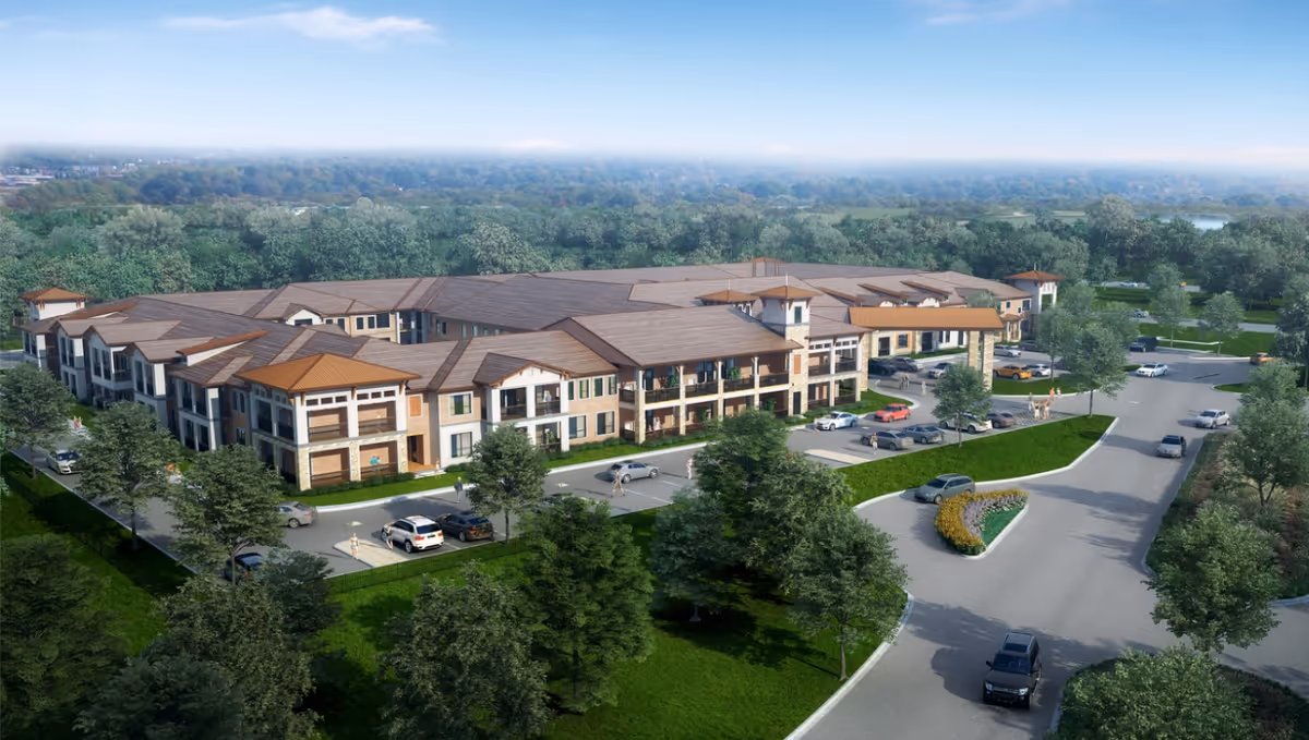 A large, multi-wing senior living facility with parking and surrounding trees.