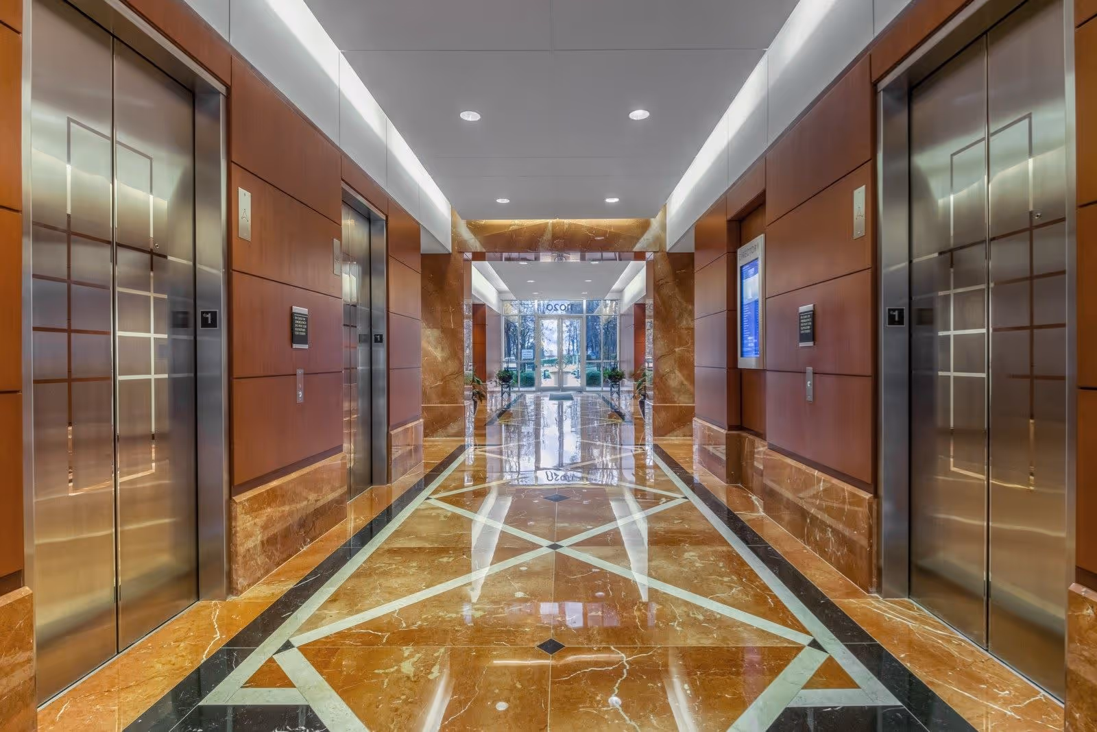 Bright marble hallway of a modern senior living facility with elevators and polished floors.