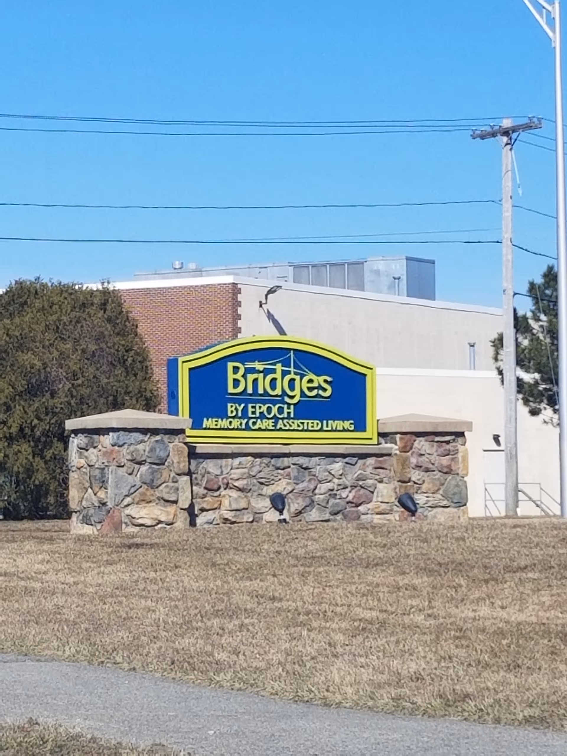 Exterior view of Bridges by Epoch at Lexington sign on stone wall with building in background.