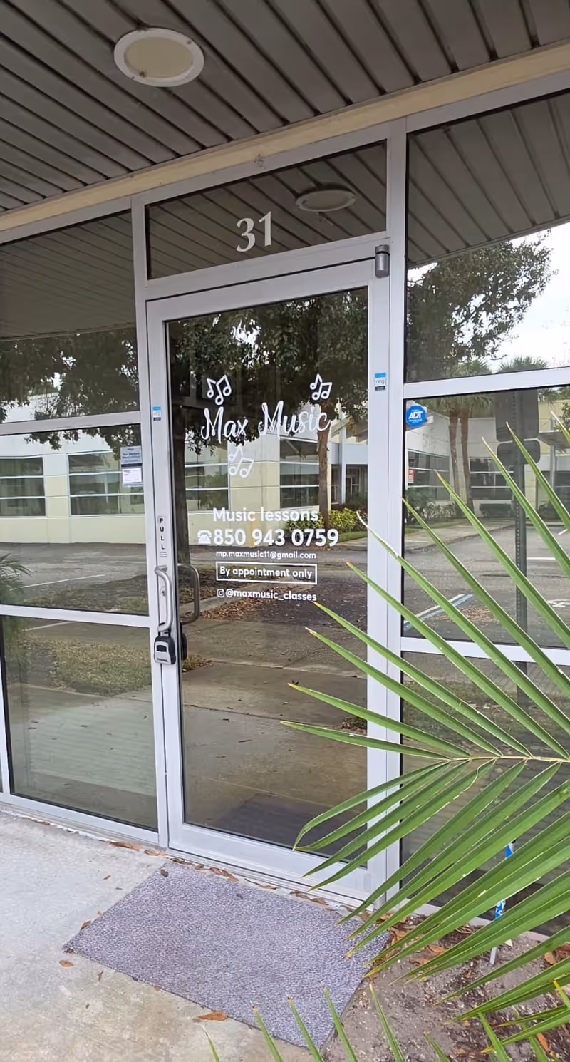 Glass entrance door labeled 31 with Max Music sign and potted plant nearby.