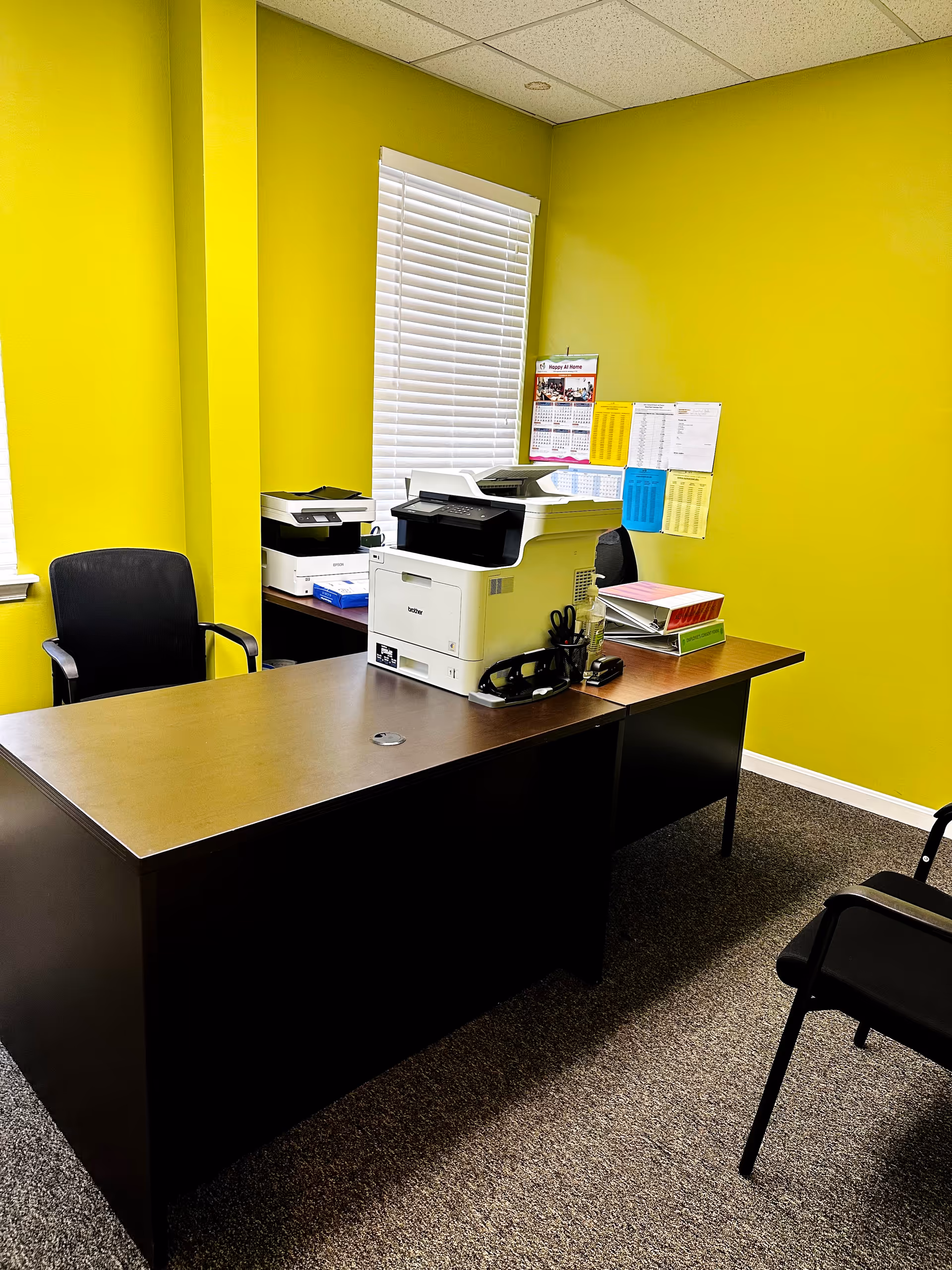 Bright lime office with desk, printer, chairs, and papers in an administrative room.