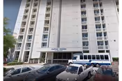 Front view of Baptist Towers, a tall white residential building with an entrance and parked cars.