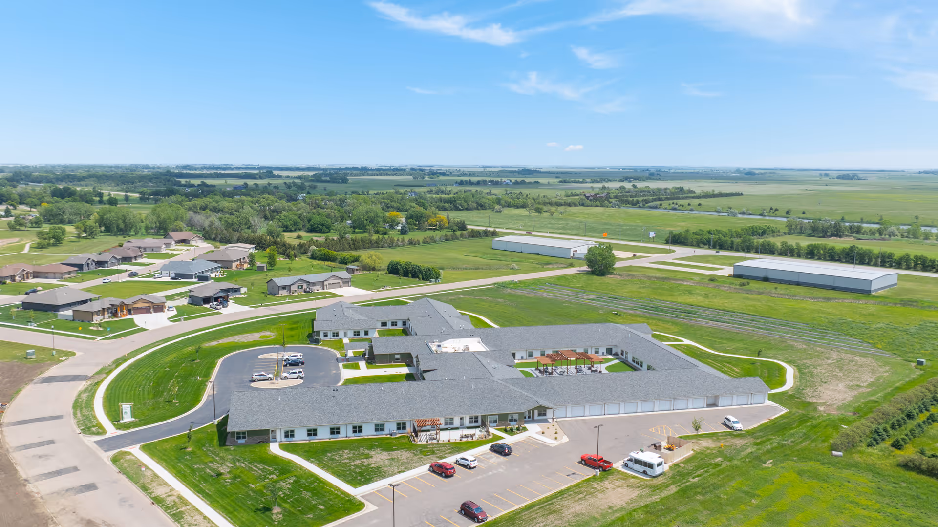 Aerial view of a senior living campus with a large, single-story building and parking.