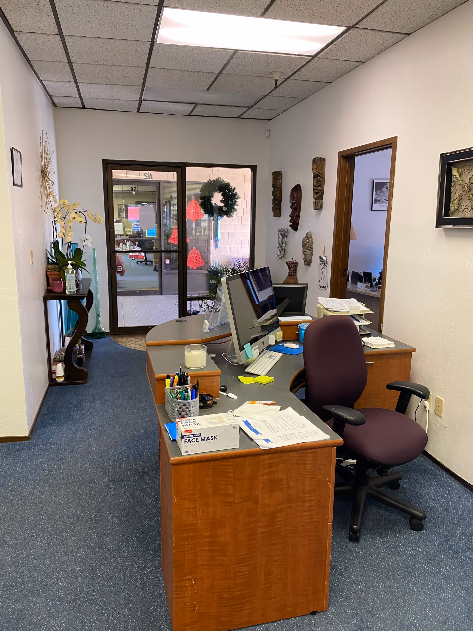 Office reception area with desk, computer, and glass entry door to outside.