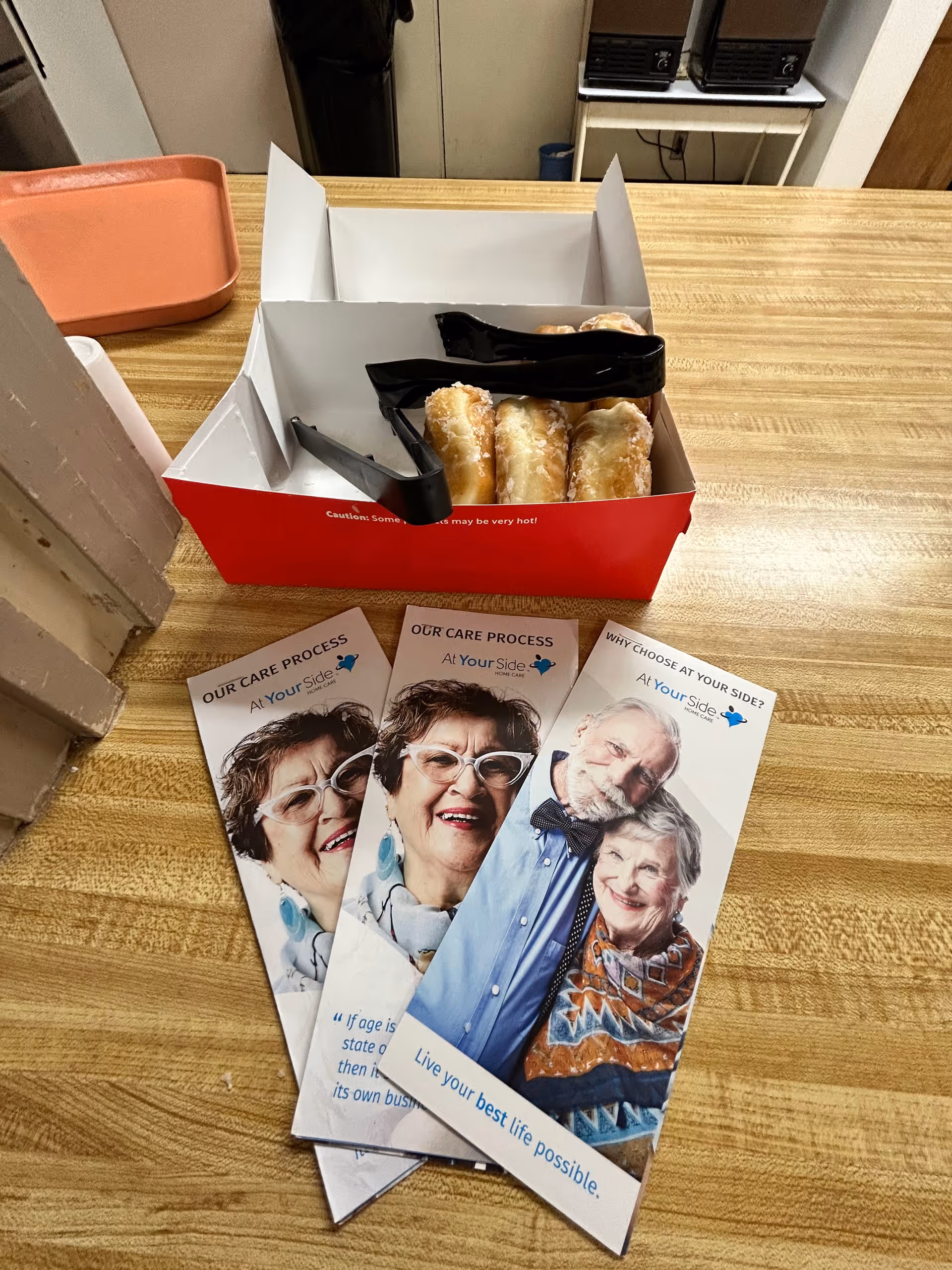 Countertop with a red donut box, tongs, and care brochures.