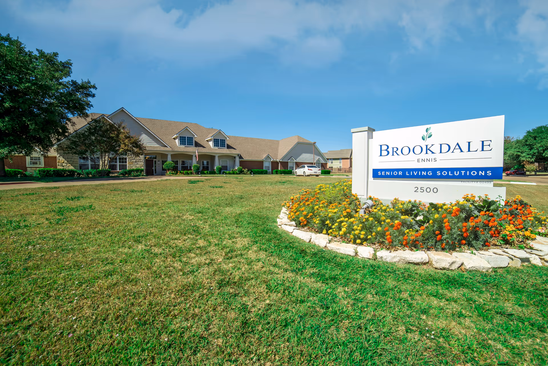 Exterior view of Brookdale Ennis senior living facility with a landscaped entrance sign