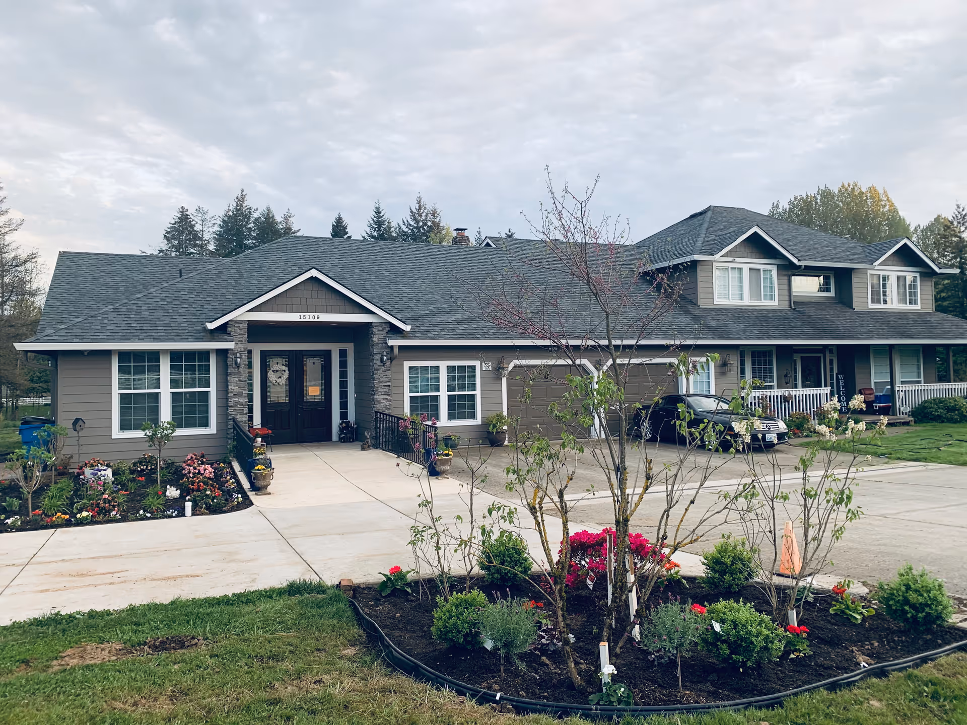 Large gray suburban style senior care facility building with driveway, cars, and landscaped front yard.