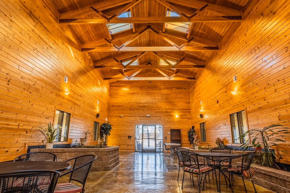 Spacious wood-paneled communal room with a vaulted ceiling and skylights, furnished with tables and chairs.