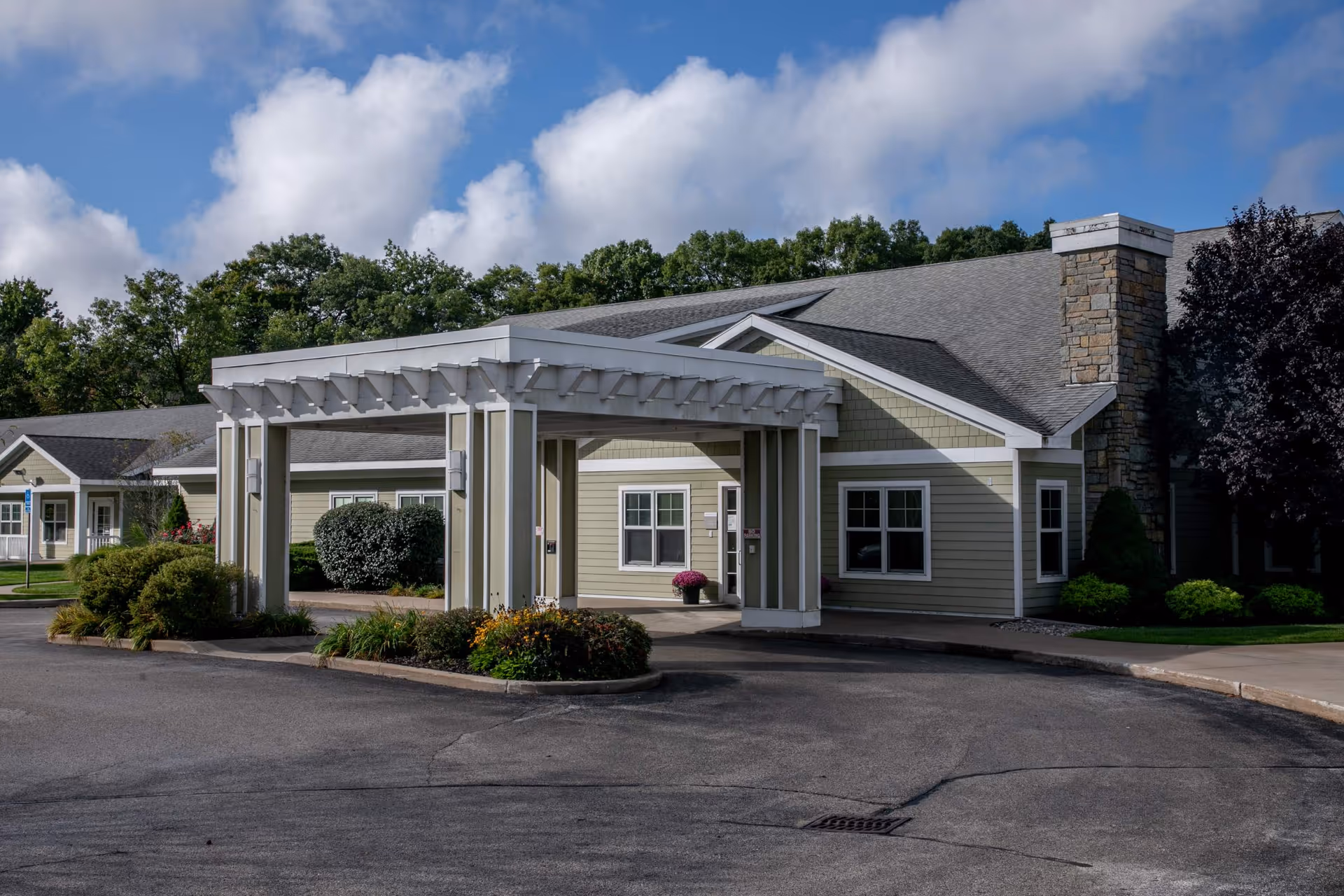 Exterior view of a senior care center with a covered entrance and landscaped circle drive.