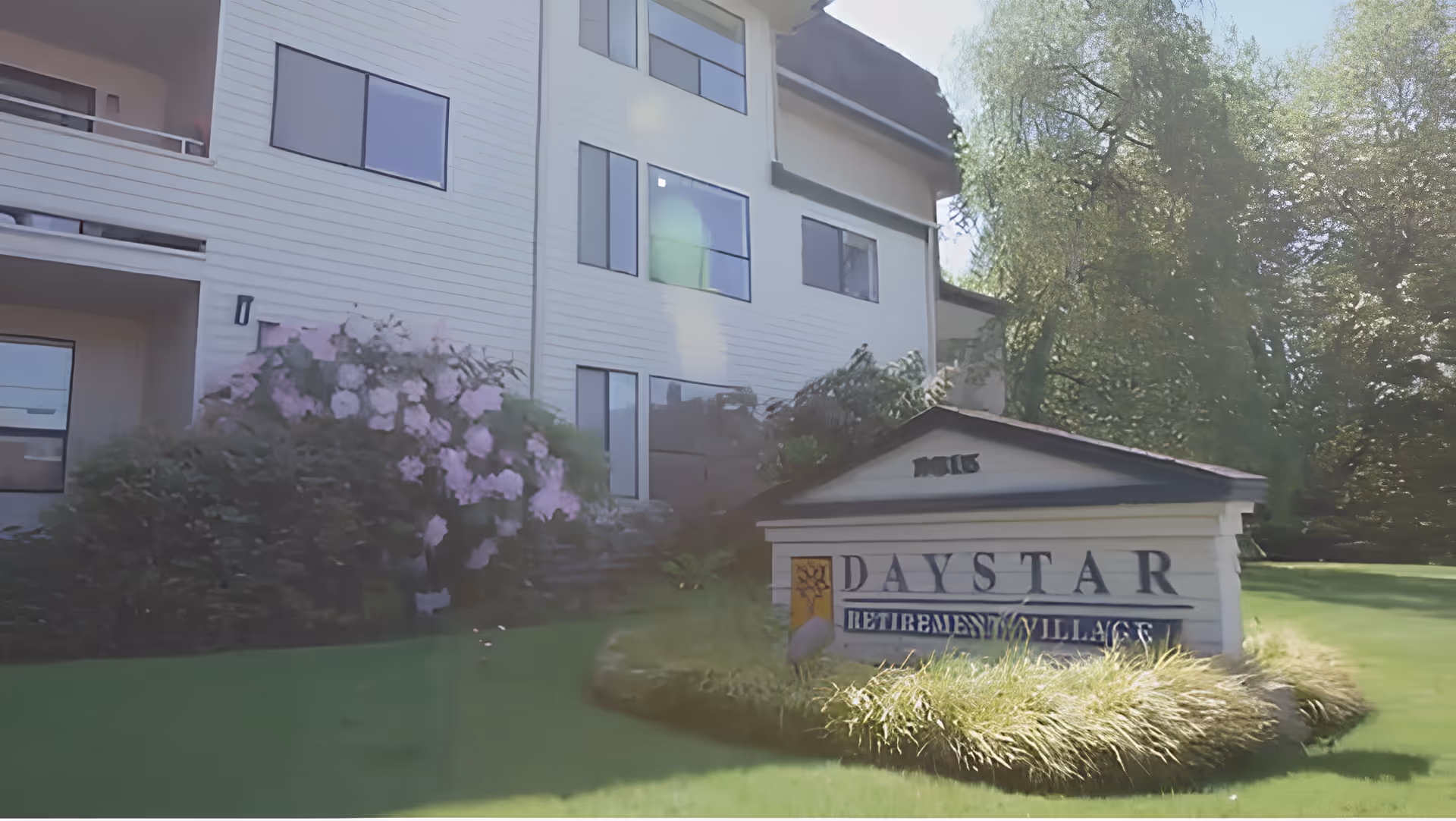 Front exterior of a multi-story retirement building with landscaping and a Daystar Retirement Village sign on the lawn.