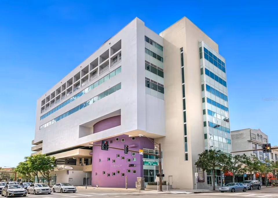 Modern multi-story senior living facility exterior with glass windows and a purple entrance.