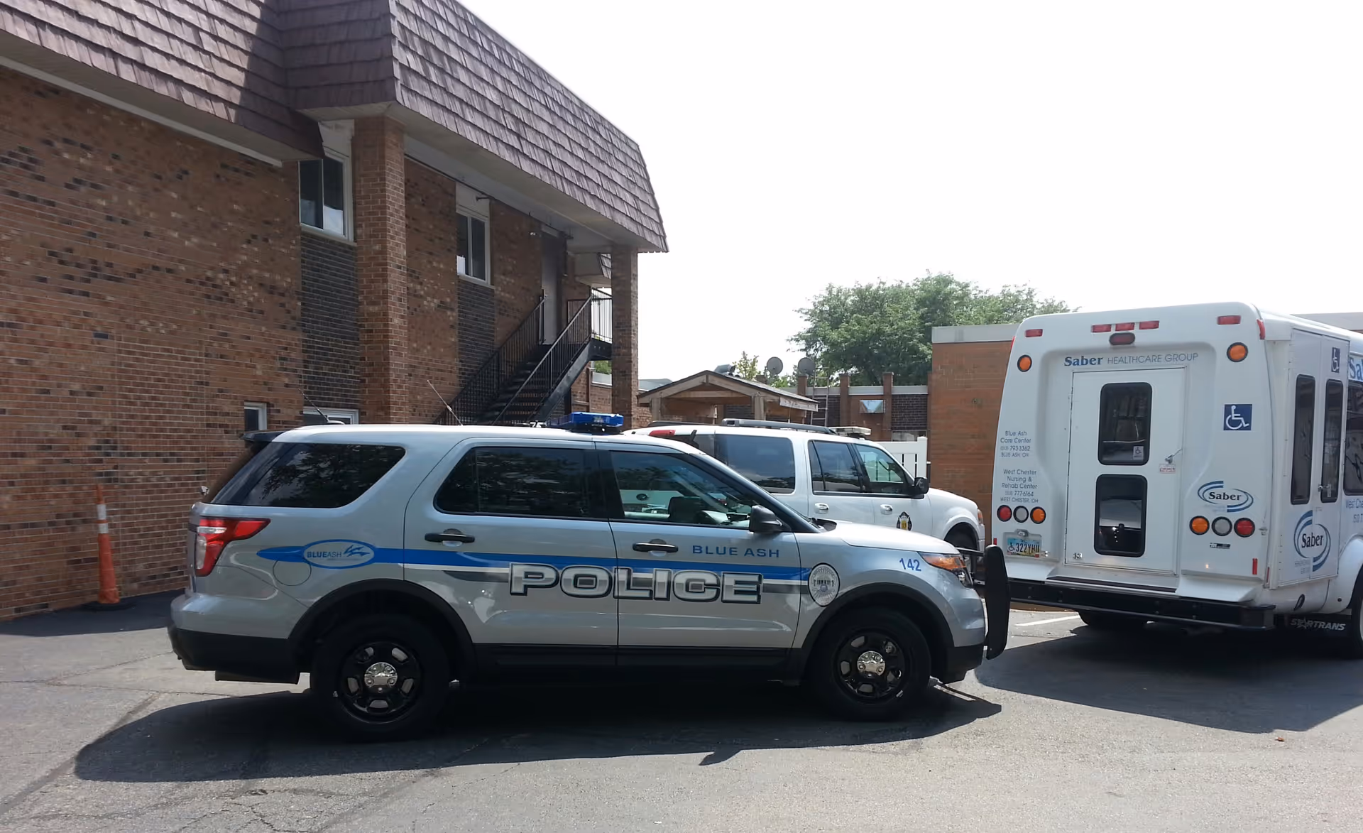Front view of Blue Ash Care Center with police vehicle and bus in the parking lot.
