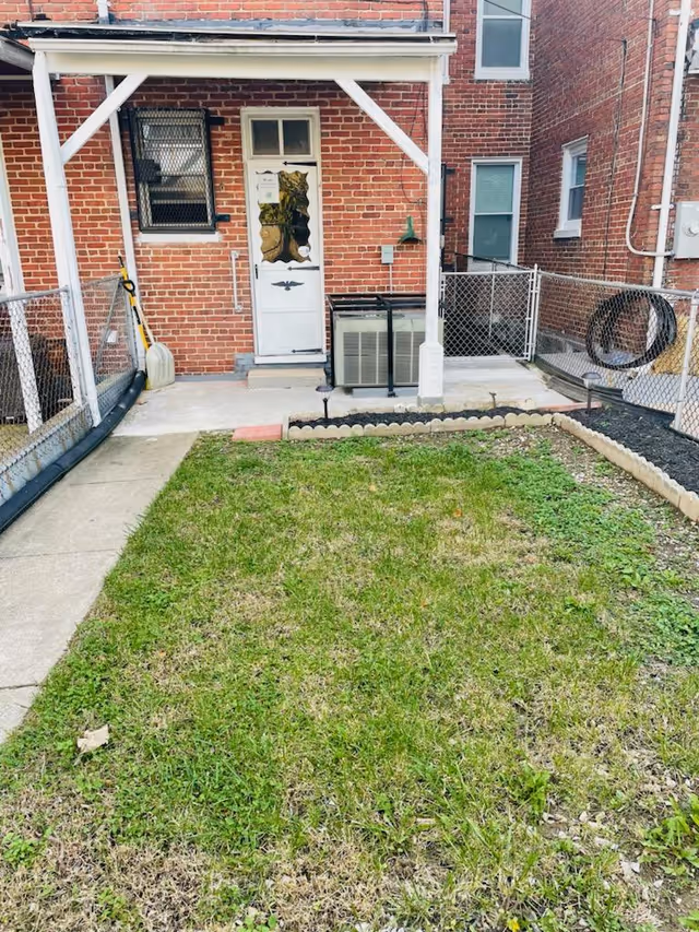 Brick exterior of a senior living facility with back door, porch, air conditioner, and lawn.