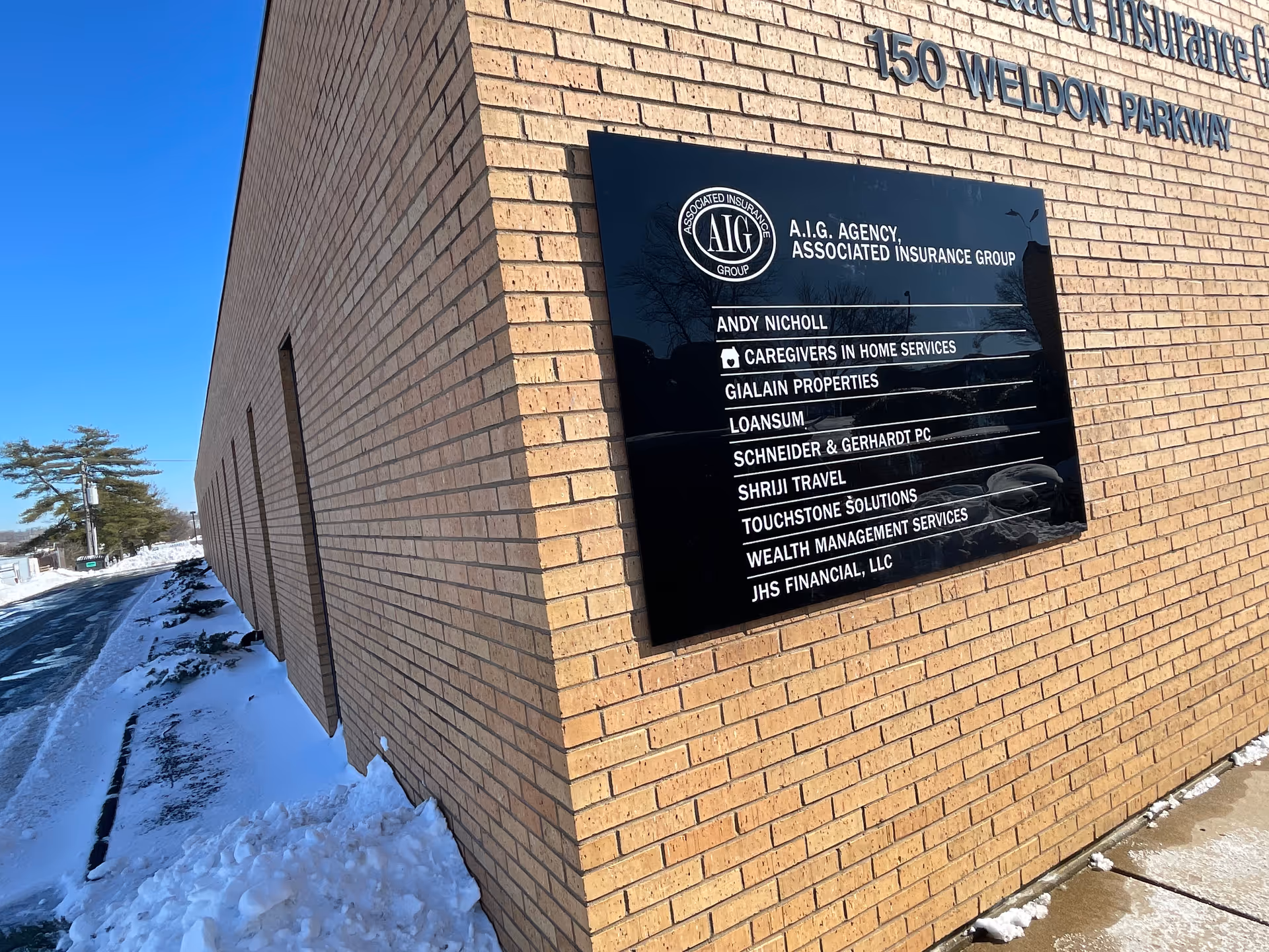 Brick building exterior with a large black directory sign listing tenants.