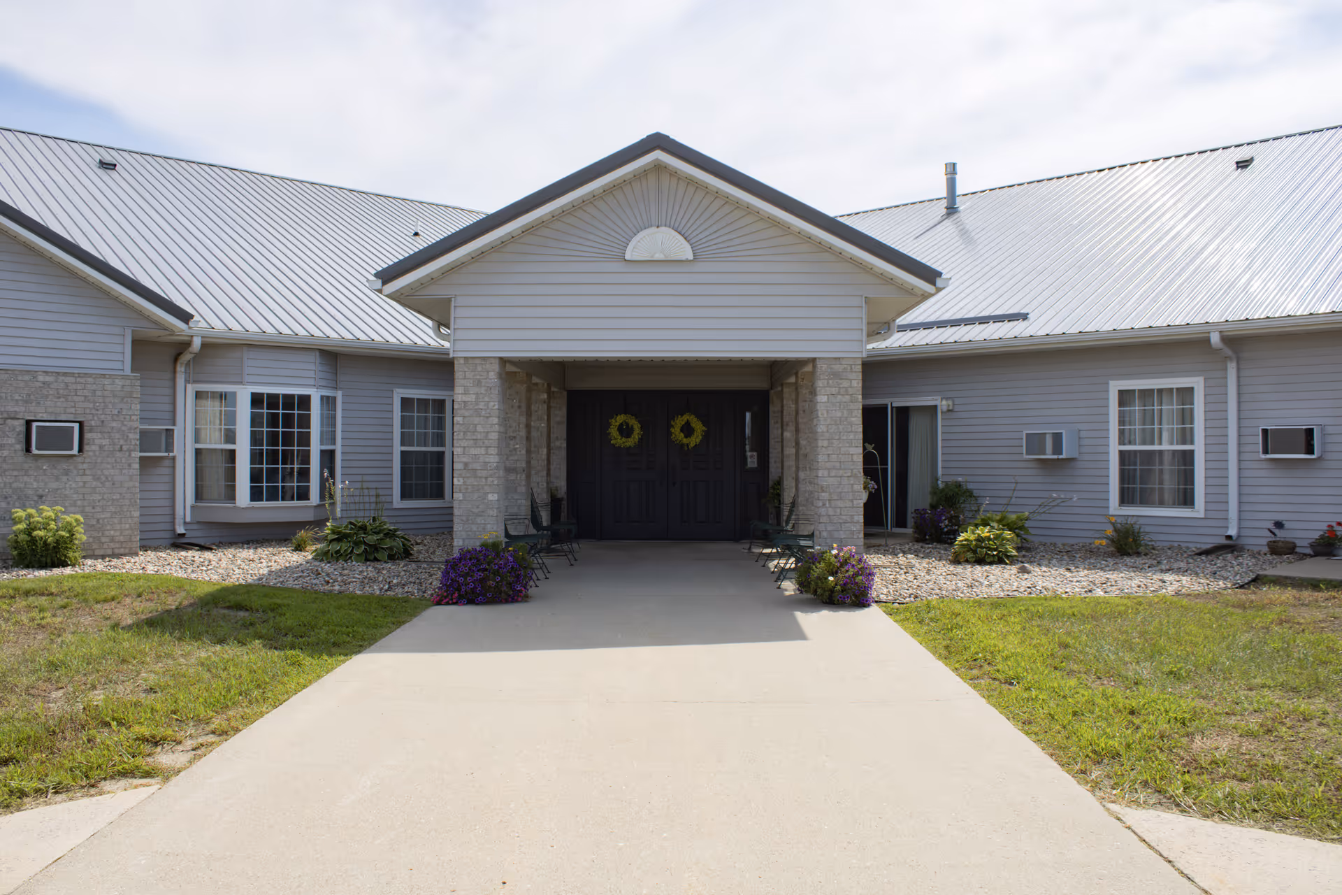 Entrance to a senior living facility with a covered front porch and double doors.