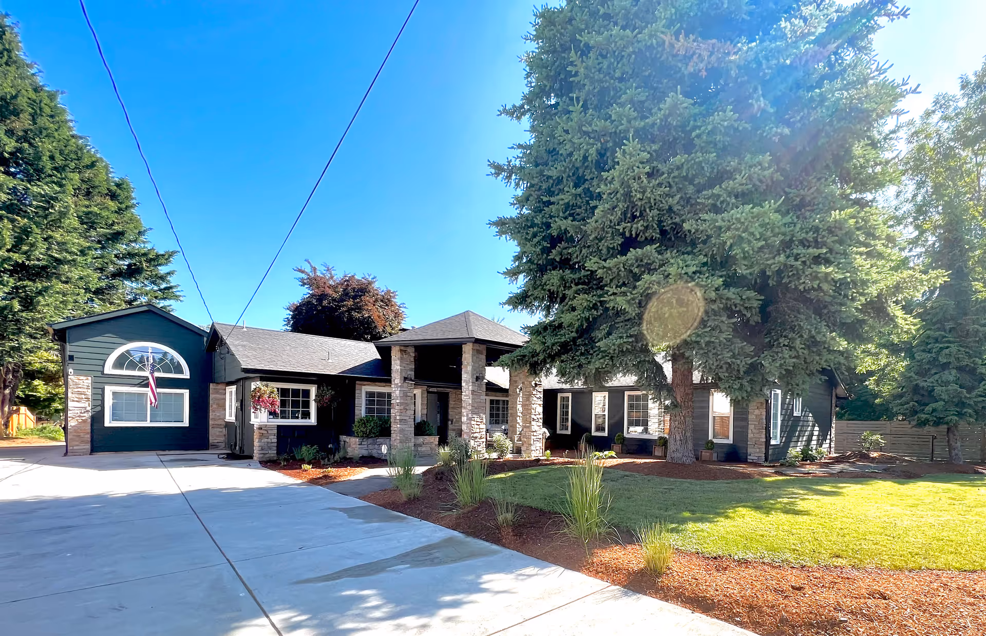 Exterior of Cinpean Residential Care: a single-story building with stone columns, driveway, and tall trees.