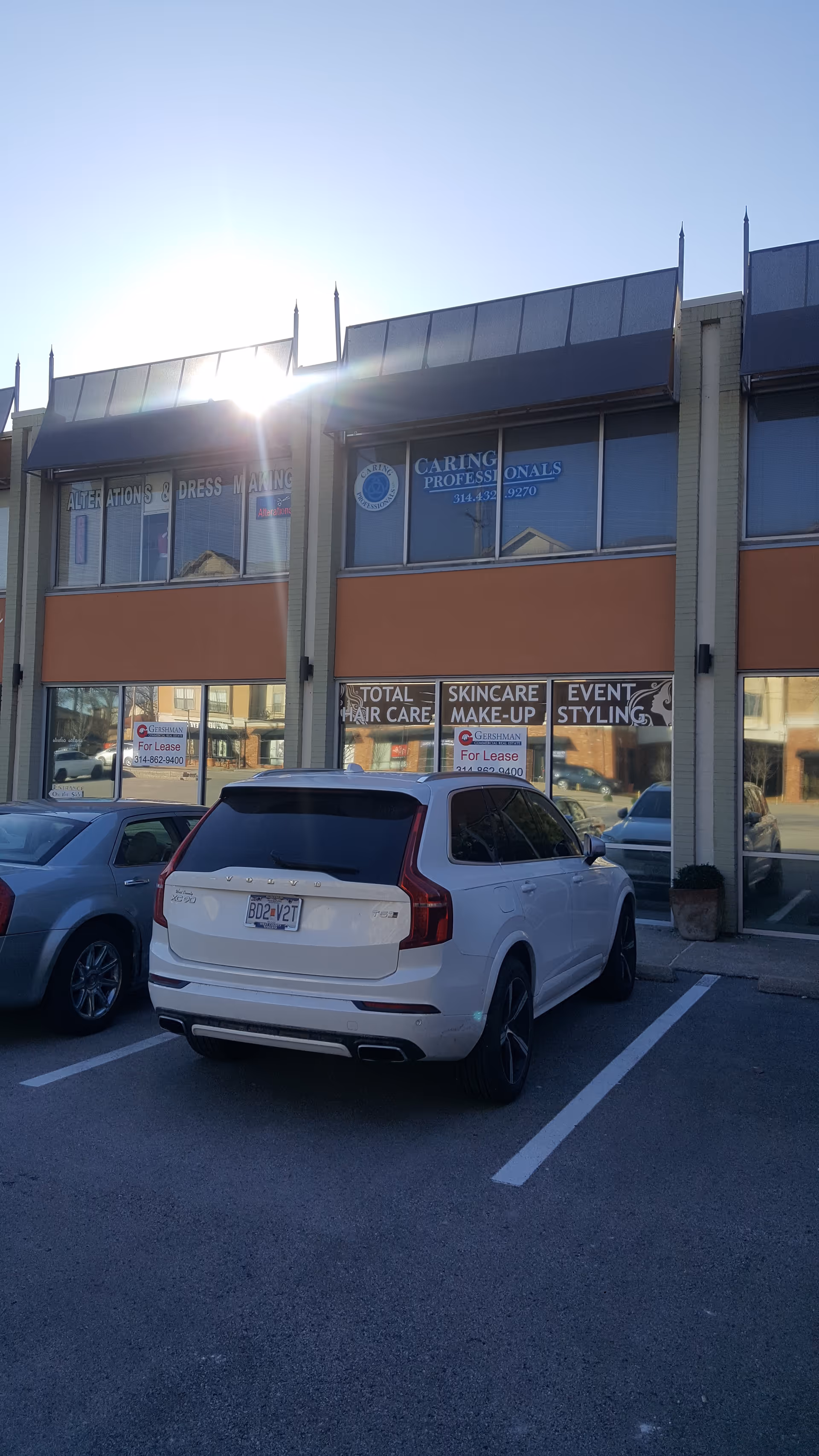 Exterior view of a strip mall storefront showing Caring Professionals signage and a parked white SUV.