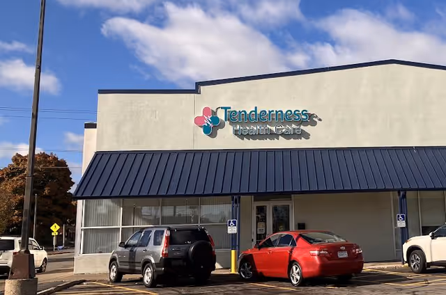 Exterior view of Tenderness Health Care facility with blue awning and parked cars.