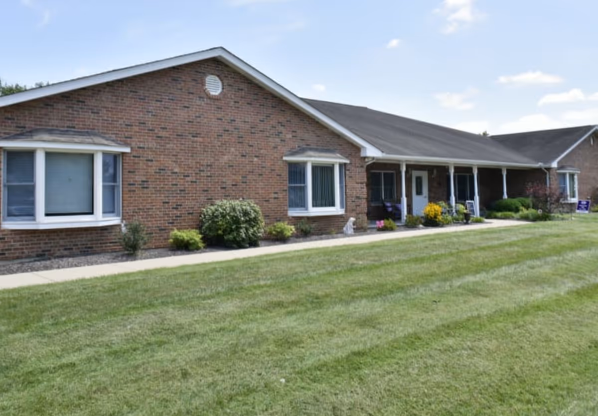 Brick senior living facility with a manicured lawn and front porch.