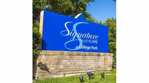 Outdoor blue signage reading 'Signature HealthCARE at College Park' atop a brick wall.