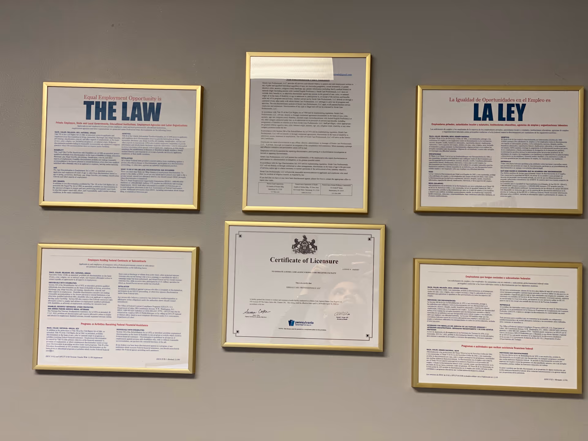 Wall features six framed documents and a certificate in gold frames.