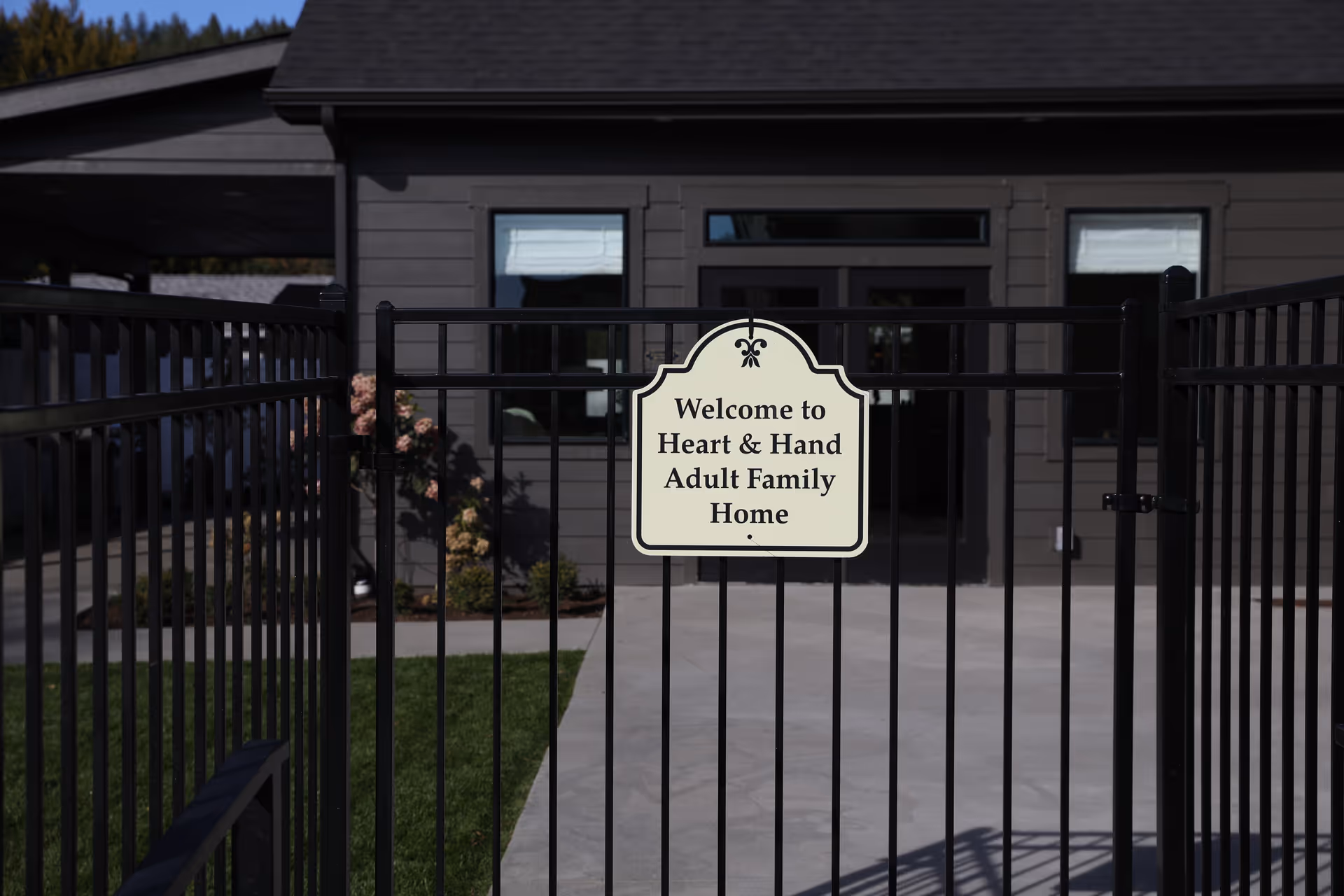 Black metal gate with sign reading Welcome to Heart & Hand Adult Family Home, front entrance