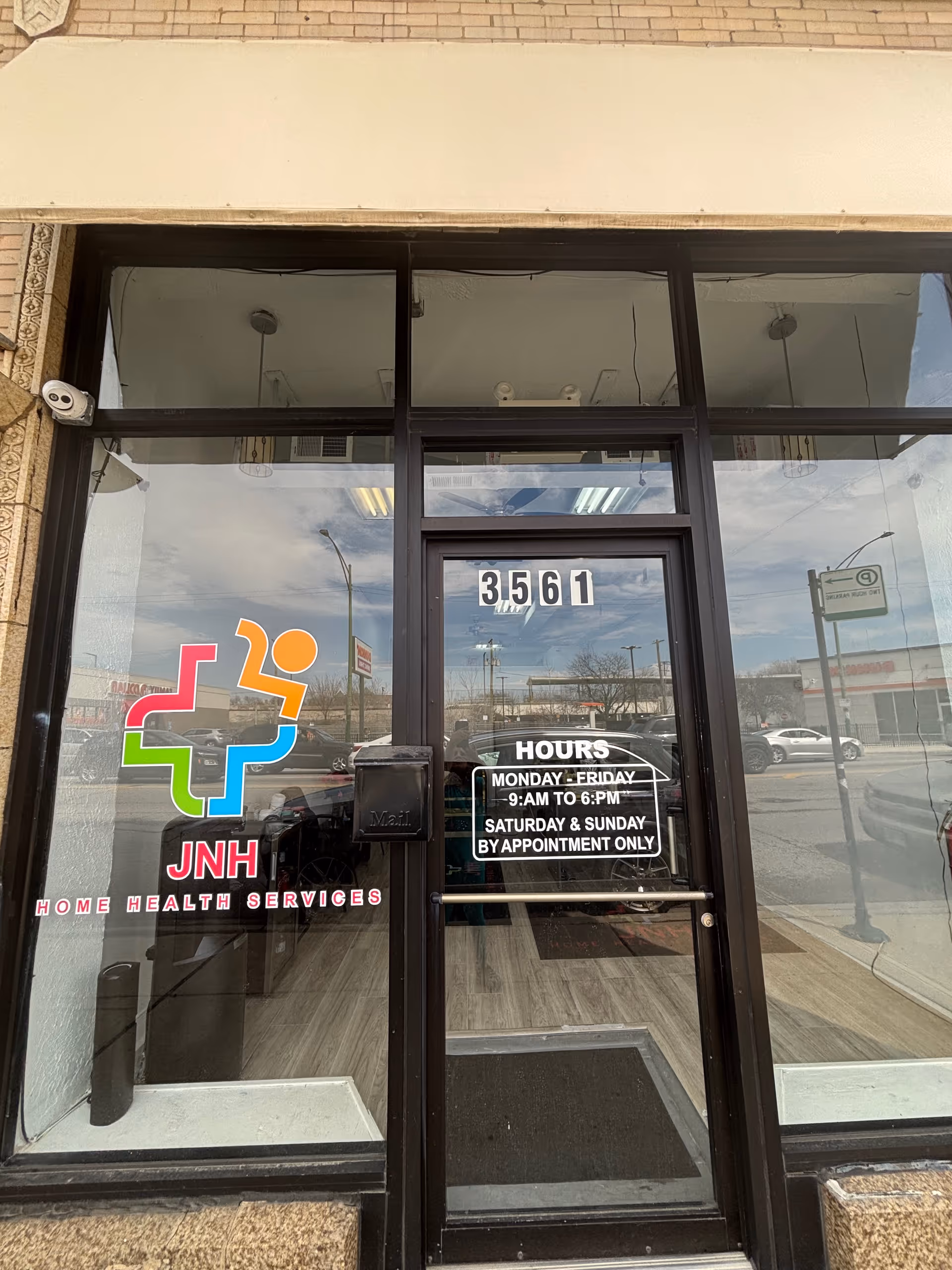Glass storefront entrance with JNH logo, address 3561, and hours displayed.