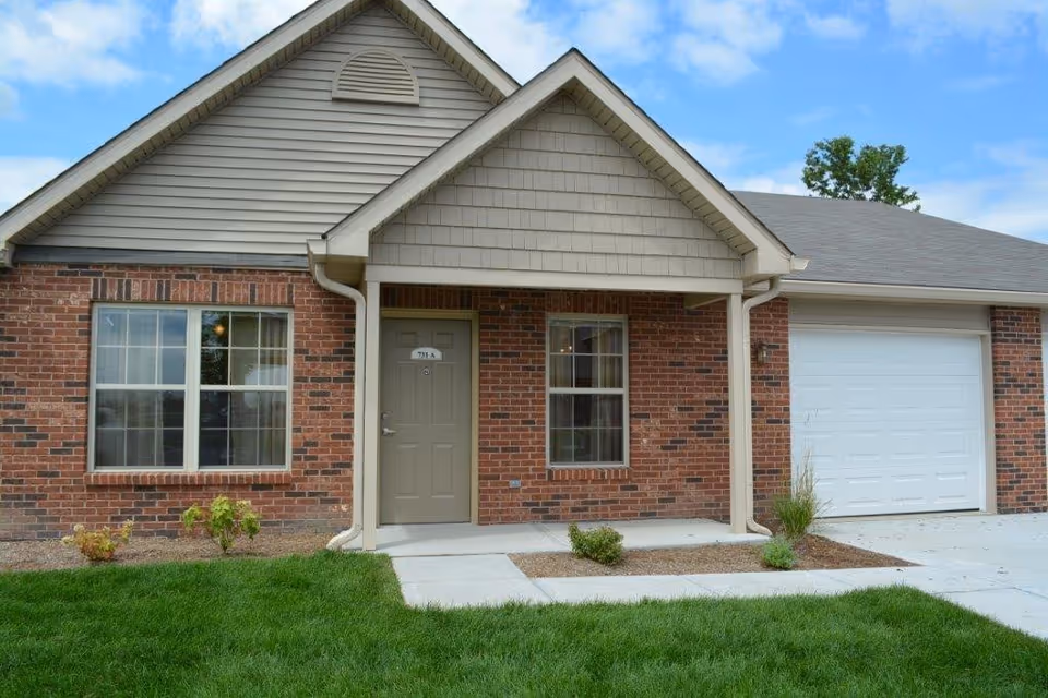 Brick senior living facility exterior with front door and attached garage.