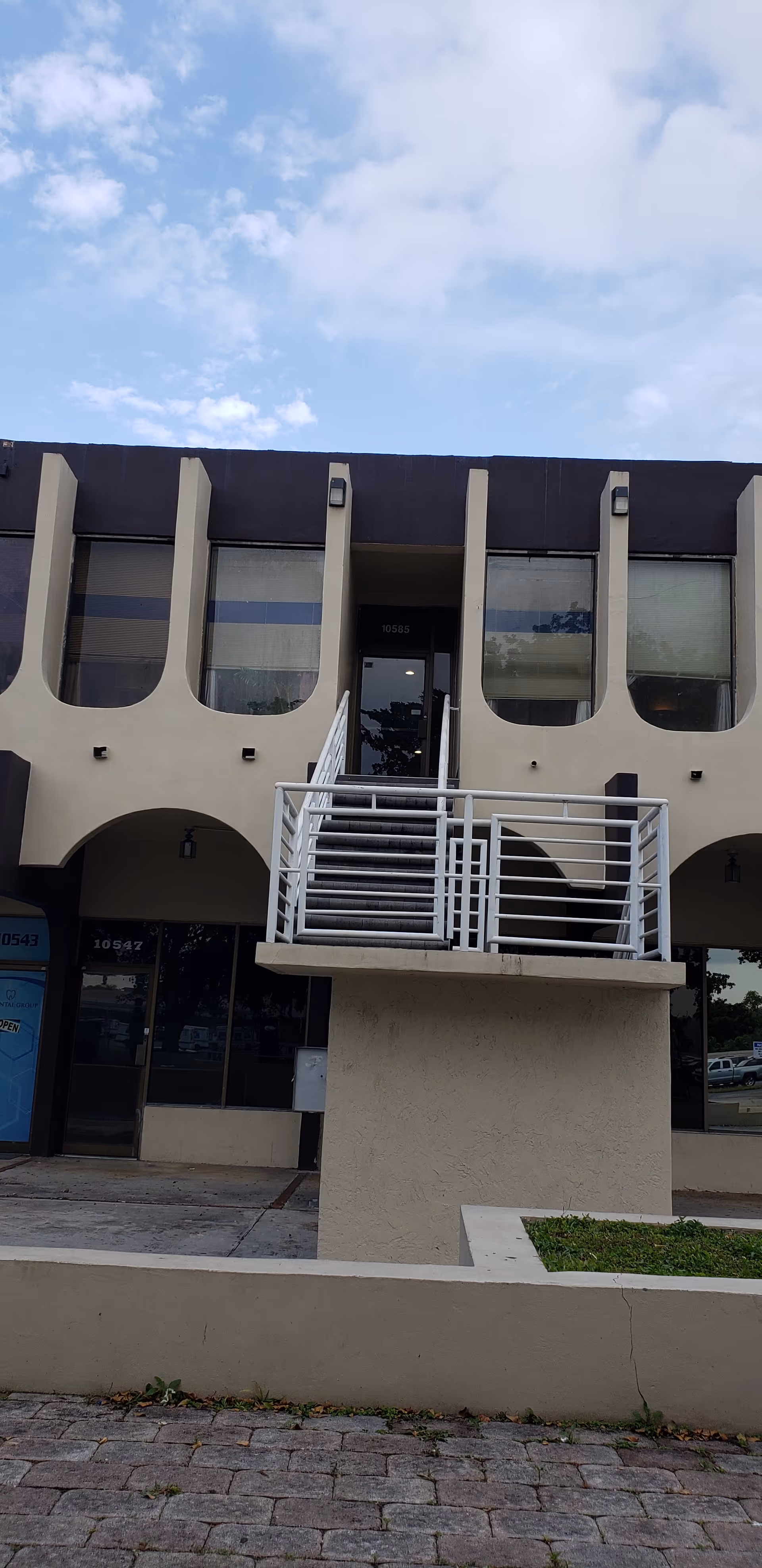 Exterior view of a two-story building with curved windows and a central staircase.