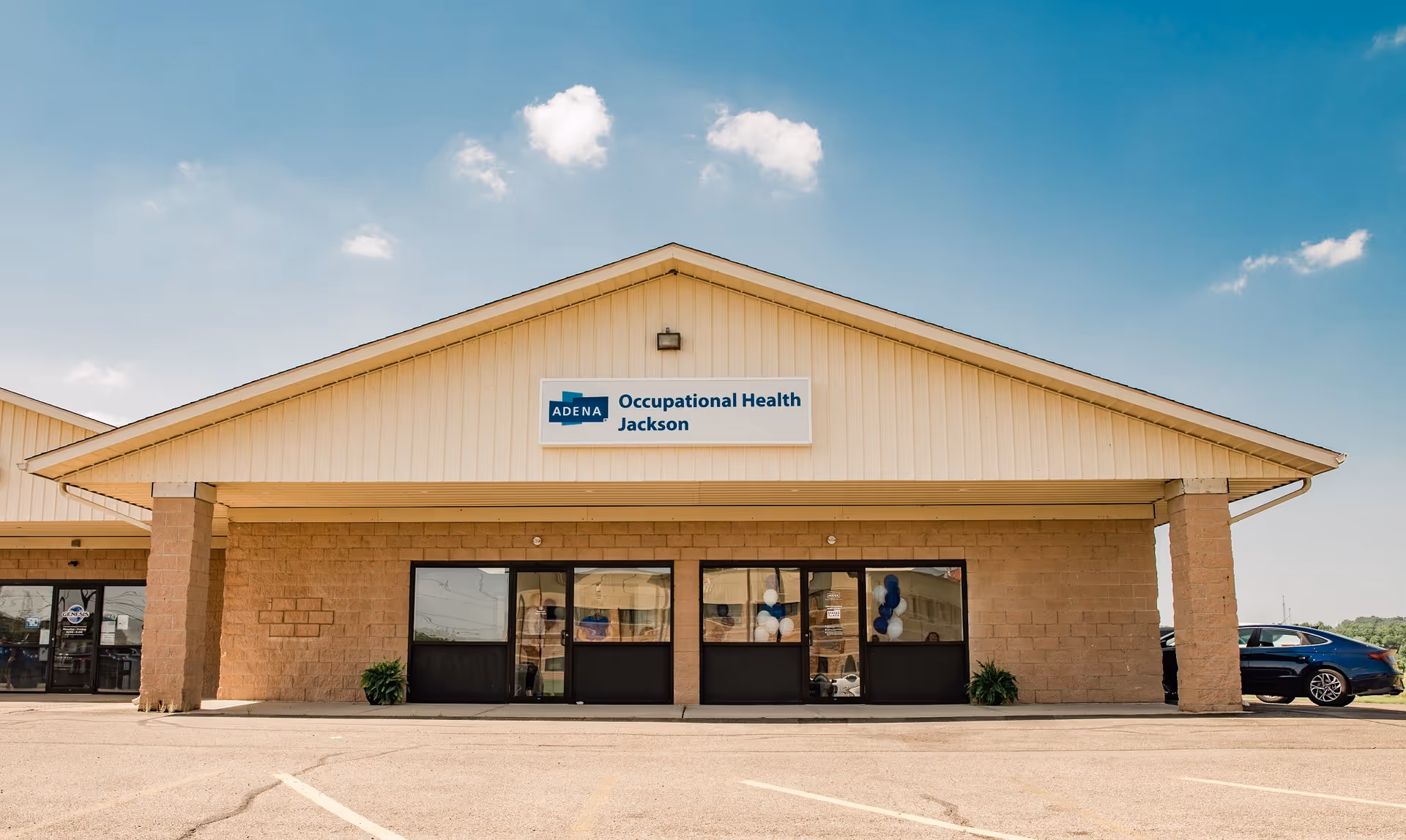 Front exterior of Adena Occupational Health Jackson clinic with sign, brick columns, and parking.