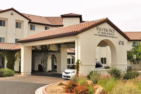 Exterior view of Silver Sky Assisted Living entrance with a curved arch and landscaping.