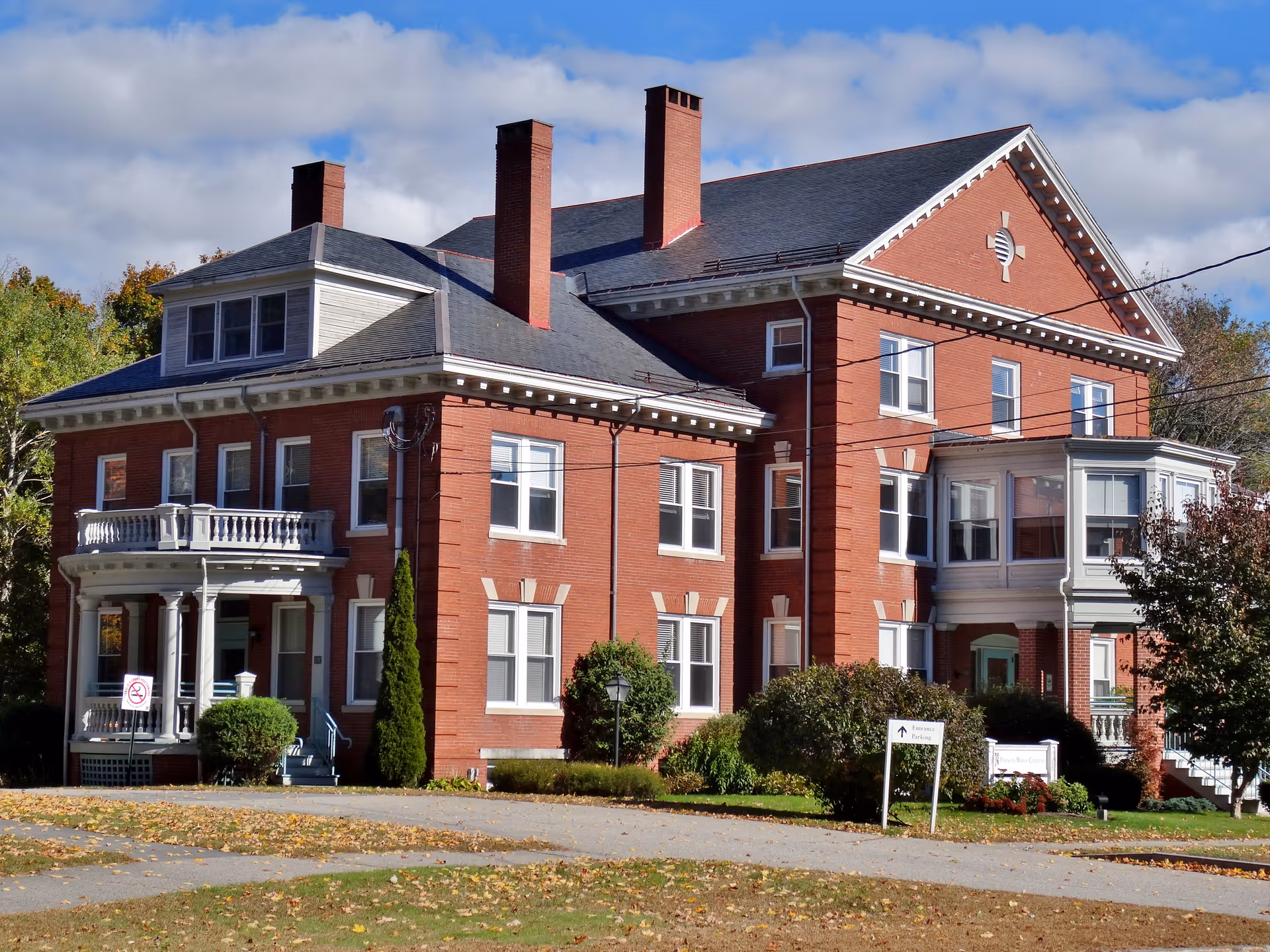 Red brick nursing home exterior with chimneys, windows, and a front porch.
