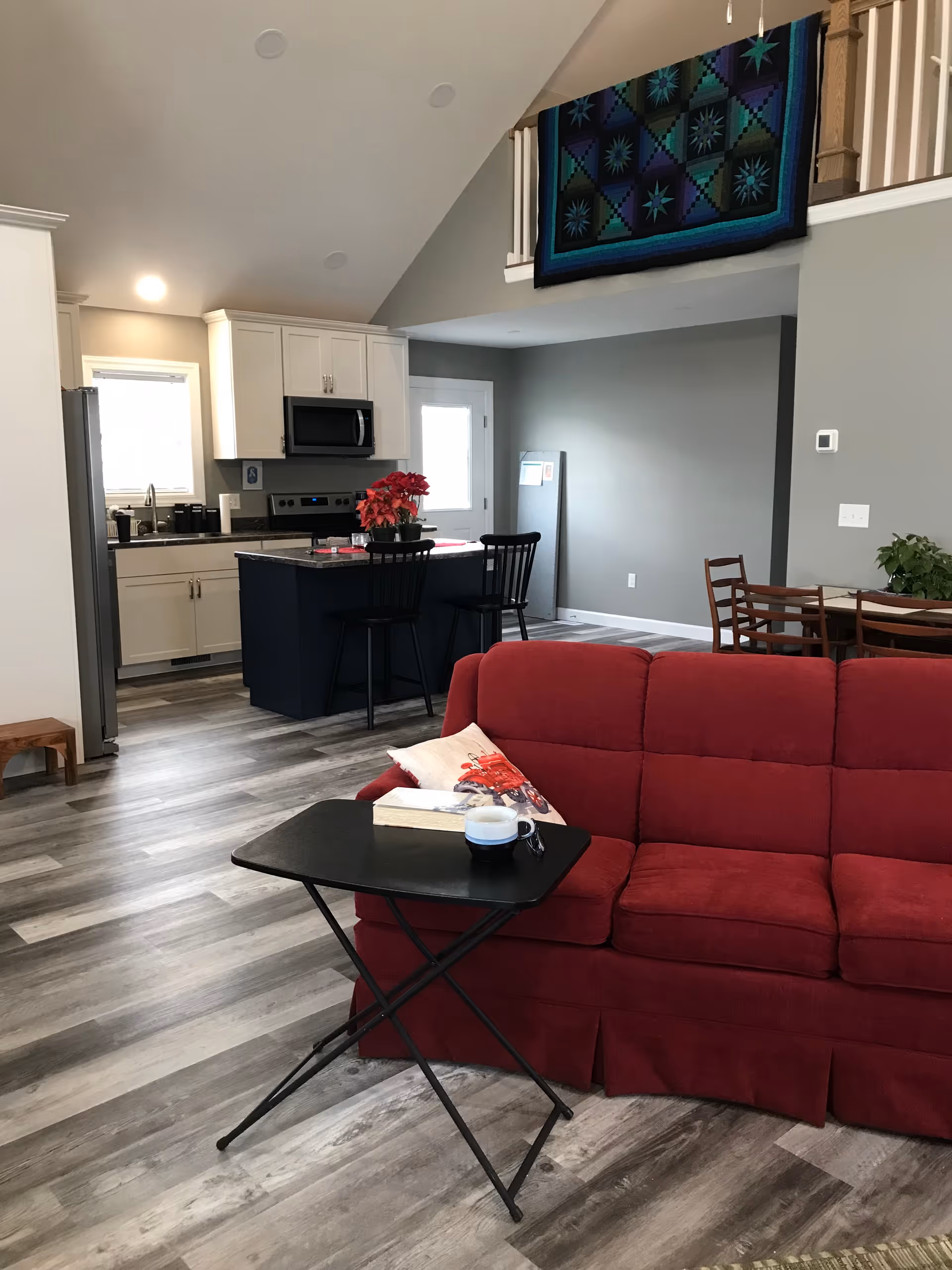 Cozy open-concept living area featuring a red sofa and kitchen in background.