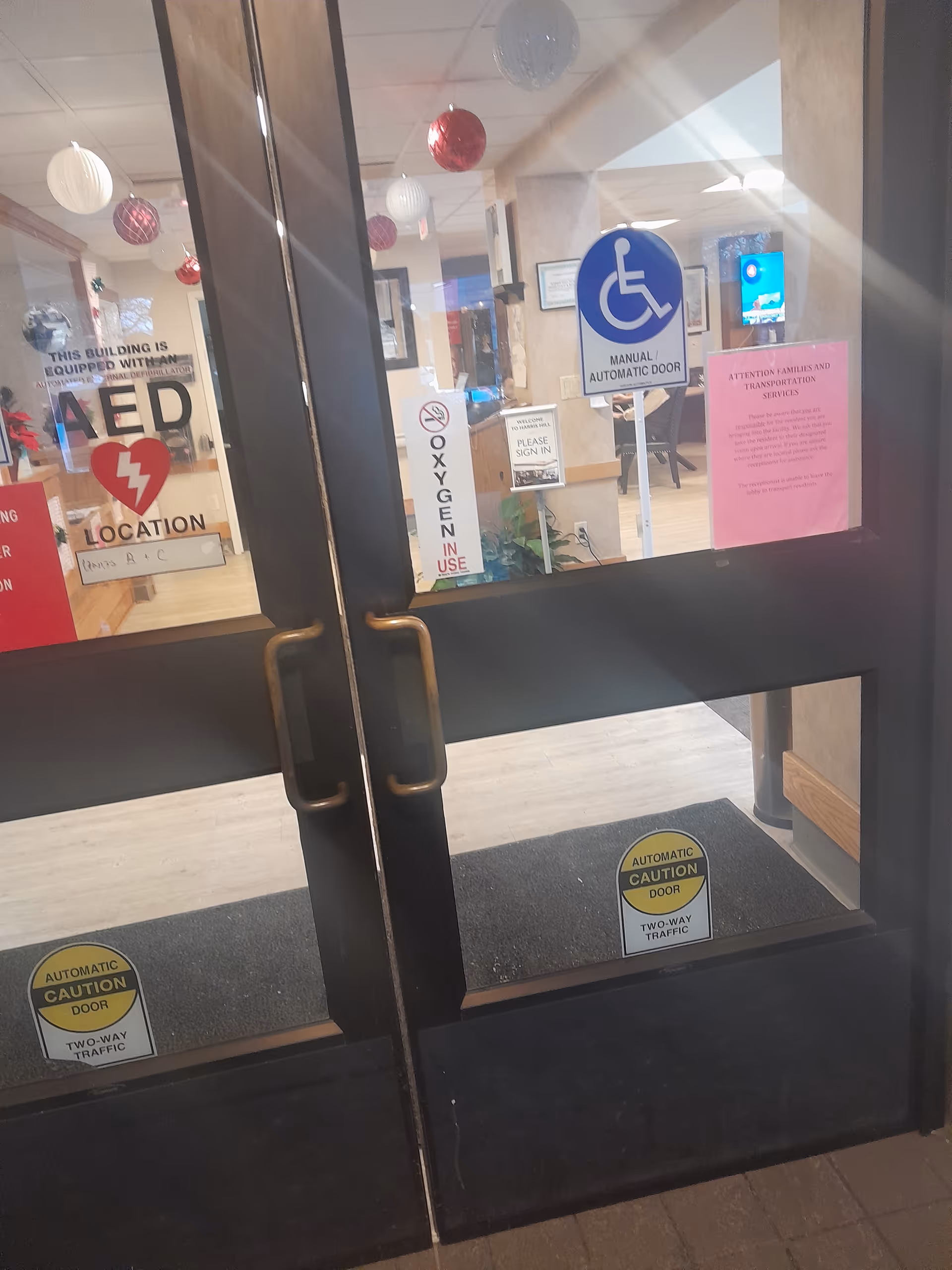Interior lobby with glass doors, handicap sign, notices, and holiday decorations.